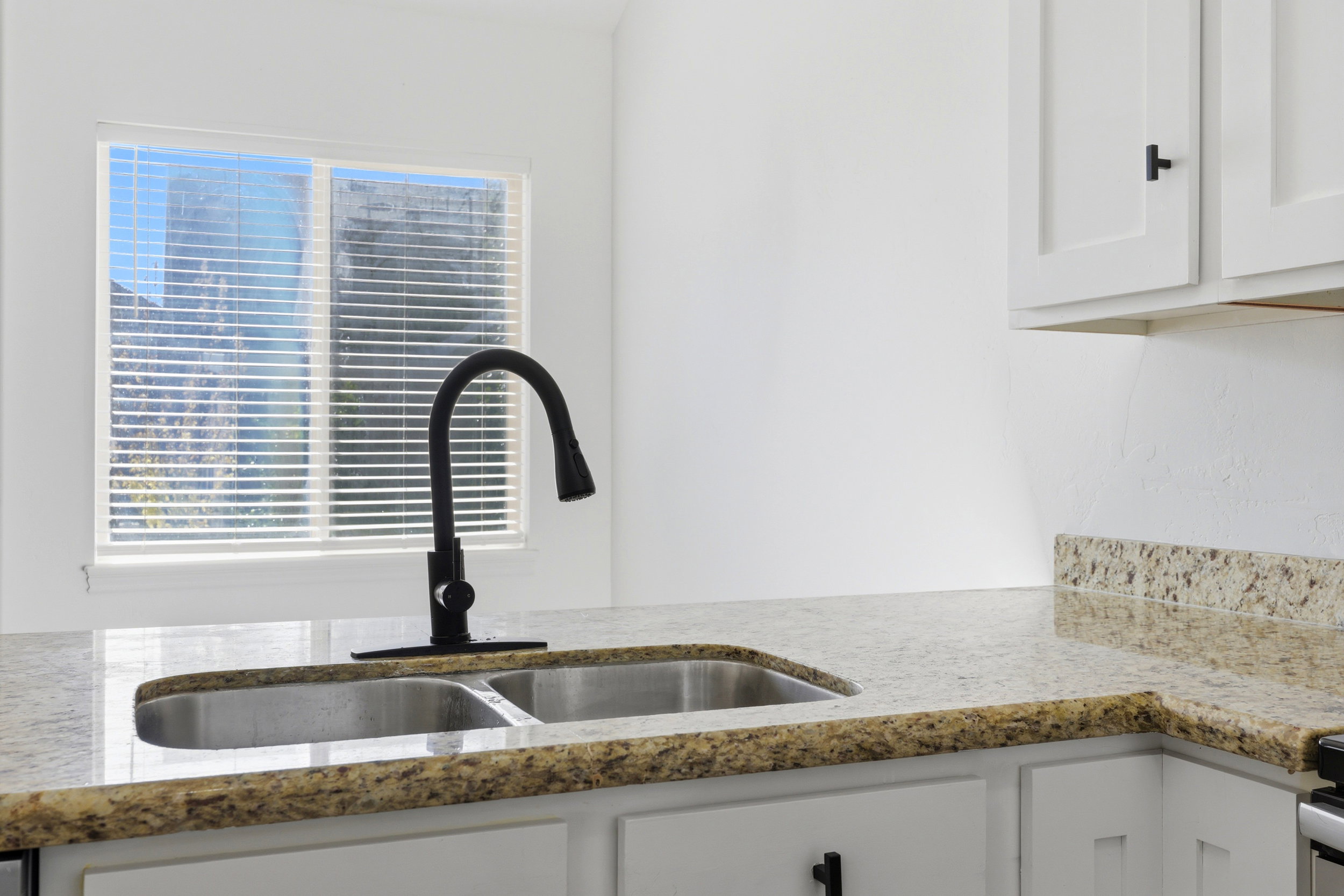 Kitchen sink with a contemporary matte black faucet, set within a speckled countertop