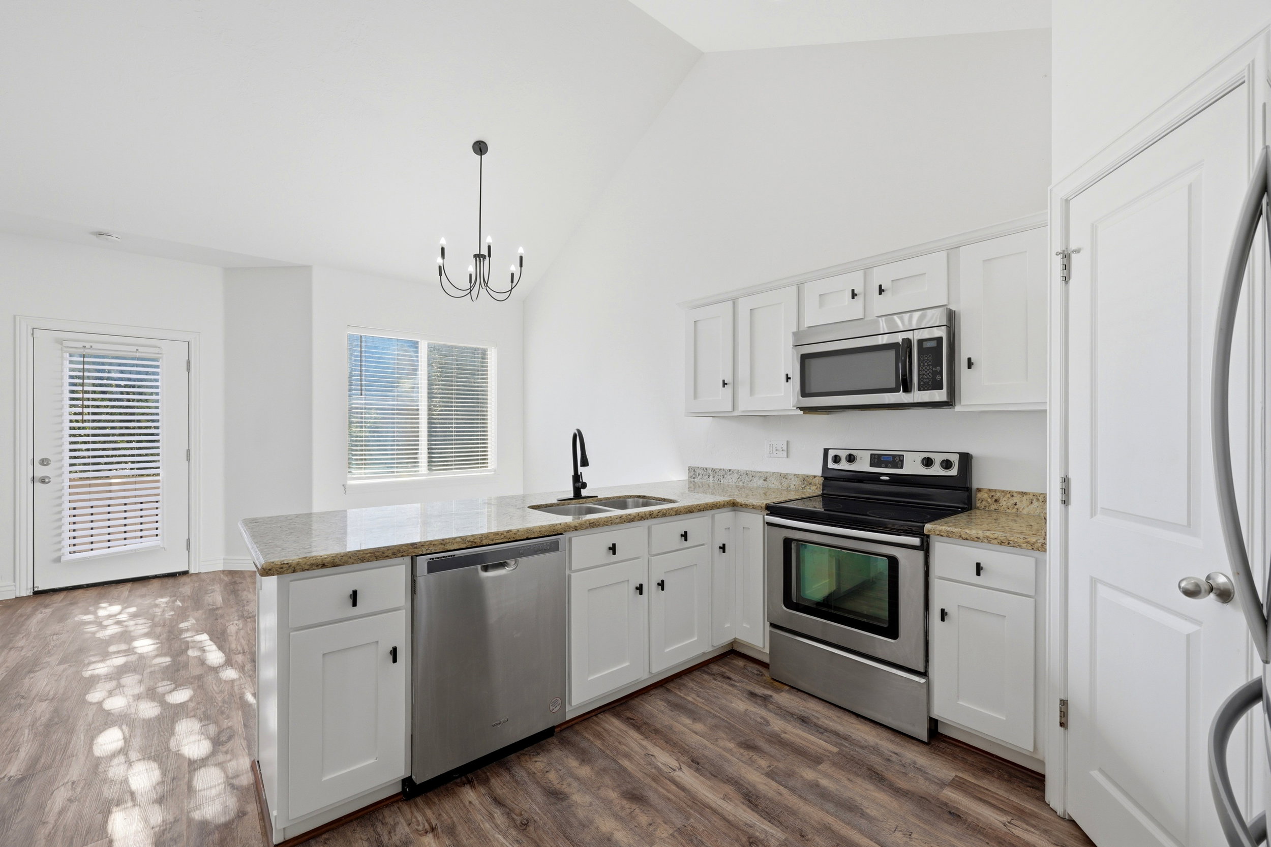 Kitchen featuring wood-finish flooring, white cabinetry, and light-colored countertops