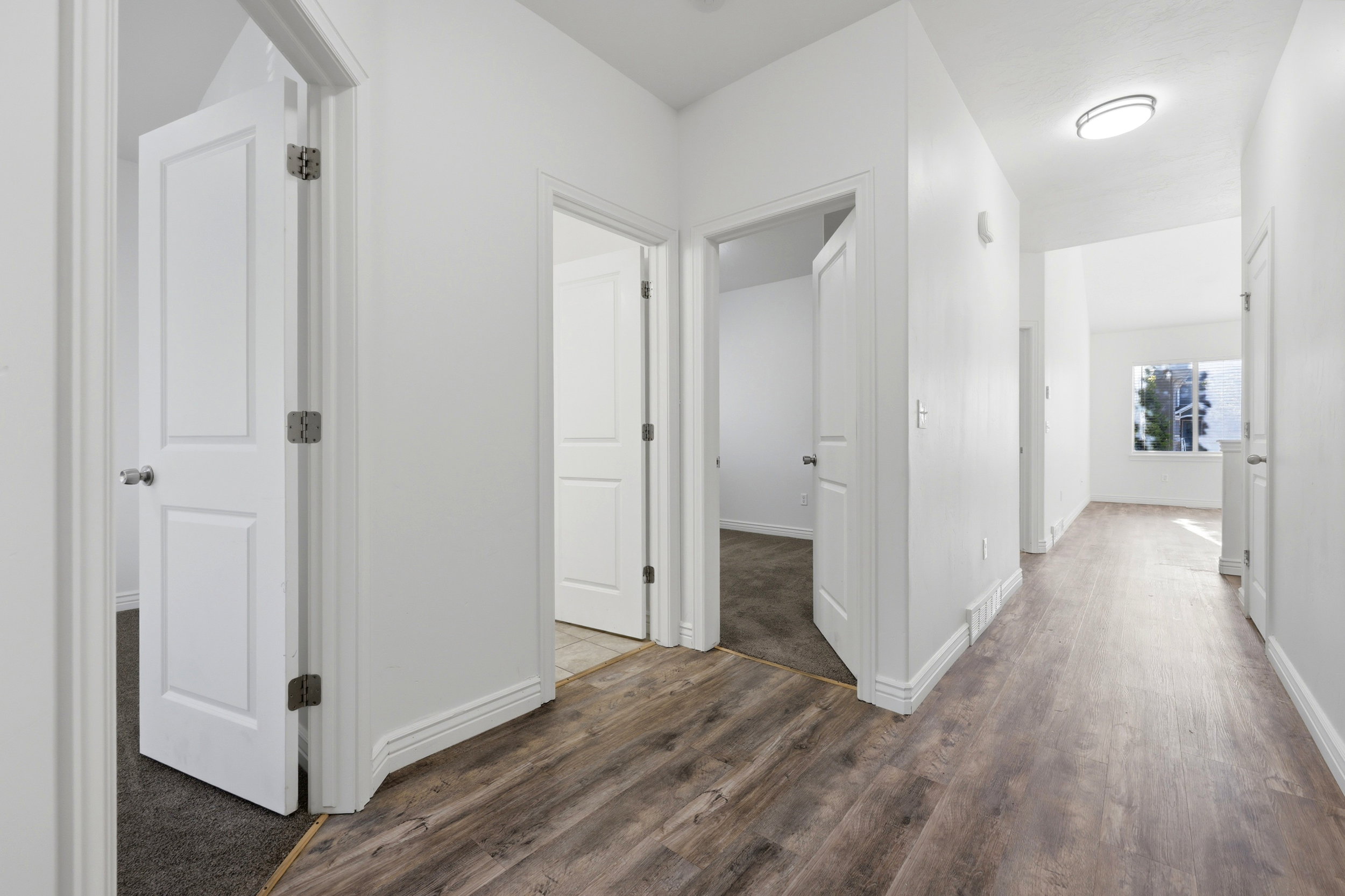 Hallway featuring wood-finish flooring, white walls, and white trim