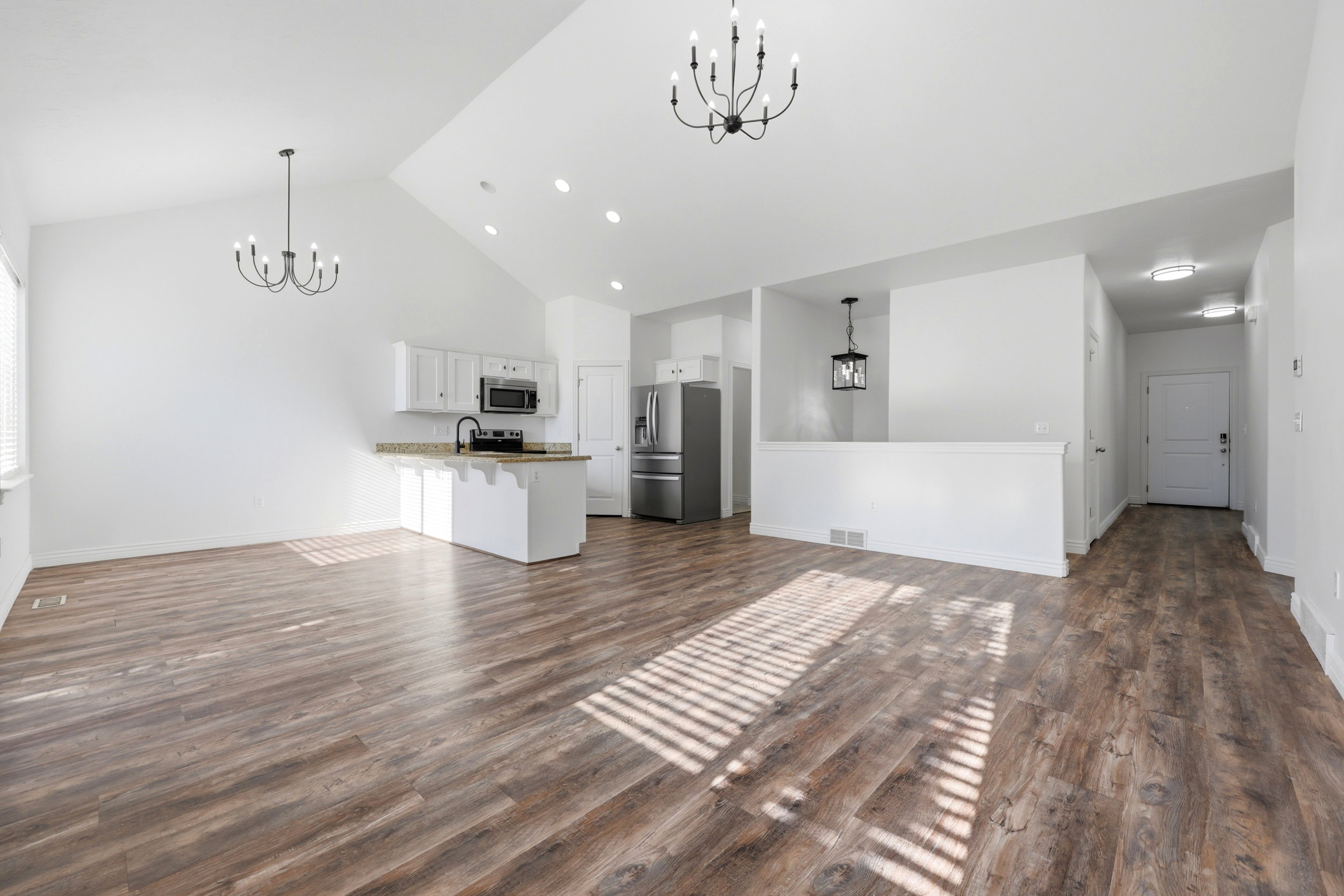 Vaulted ceilings enhance this open-concept living area with wood-finish flooring