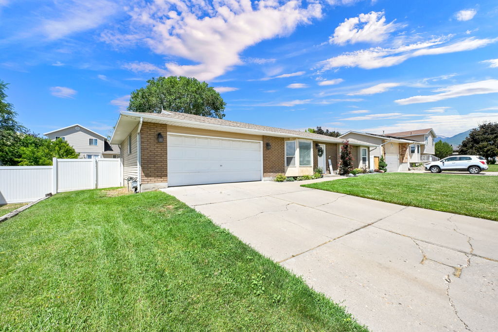 Ranch-style residence featuring a brick facade, attached garage, and white vinyl fencing