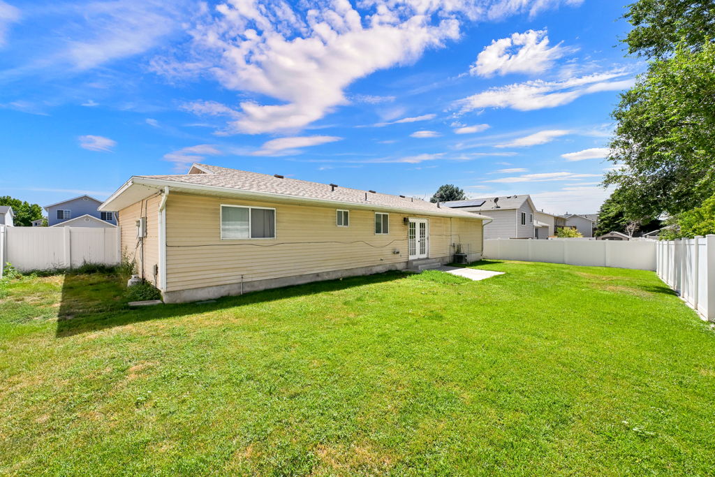 Expansive green lawn surrounds the property, complemented by a white vinyl privacy fence