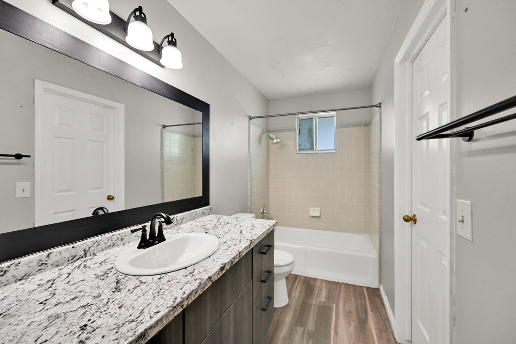 Bathroom featuring a vanity with a patterned countertop, undermount sink, and dark wood-finish cabinetry