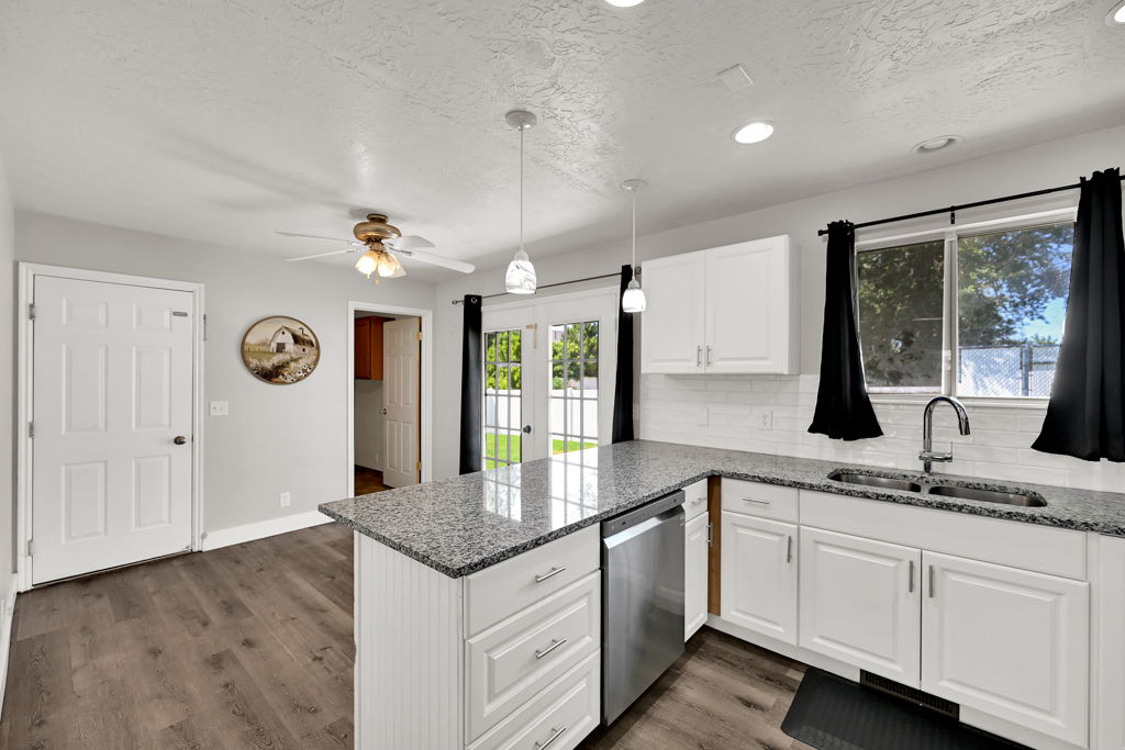 Kitchen featuring white cabinetry, granite countertops, stainless steel dishwasher, and wood-finish flooring
