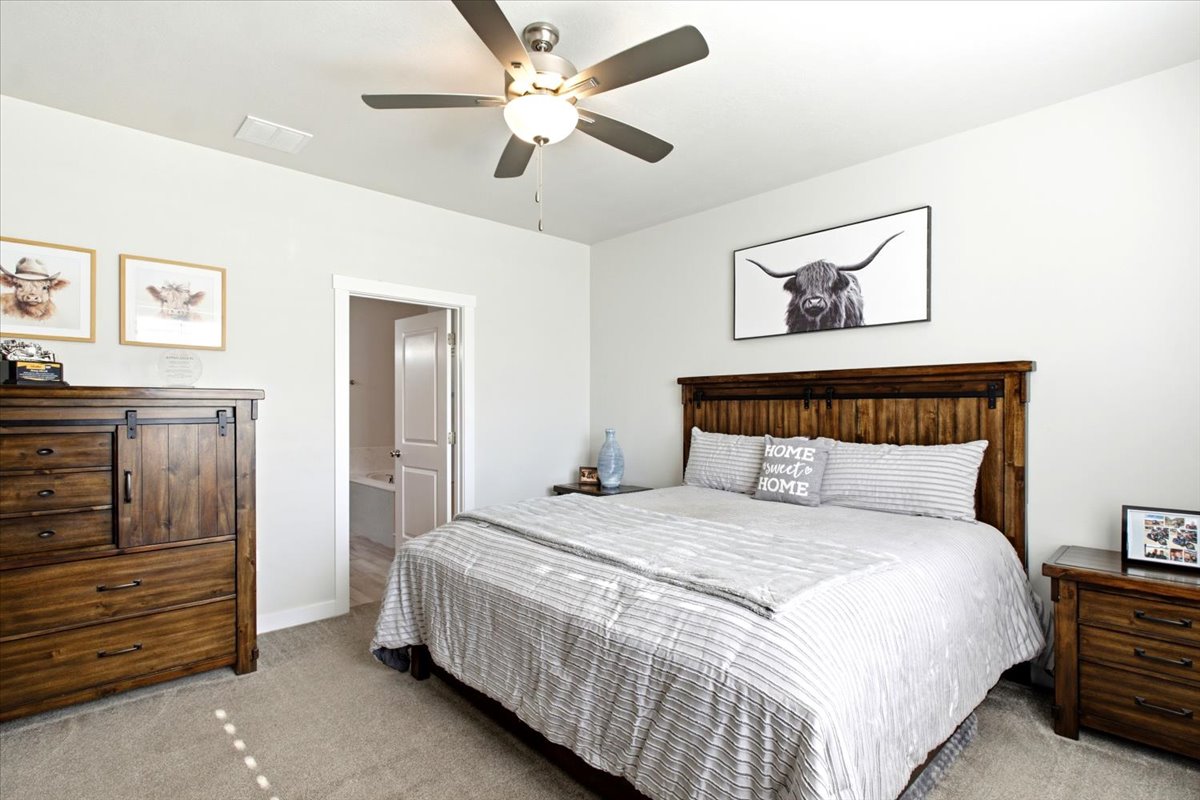 Bedroom featuring a wood headboard, neutral wall paint, ceiling fan with integrated lighting, and carpet flooring