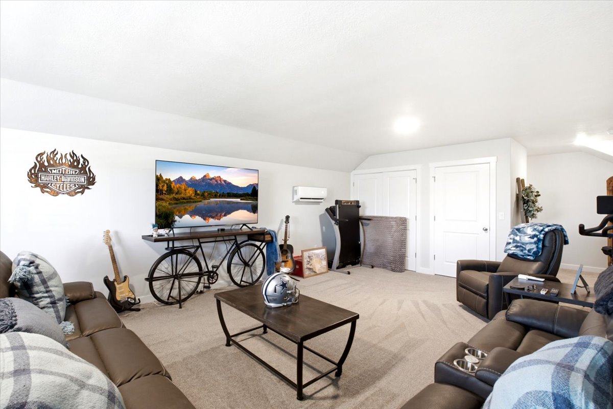 Spacious bonus room featuring neutral carpeting, a white ceiling with recessed lighting, and a wall-mounted mini-split HVAC unit