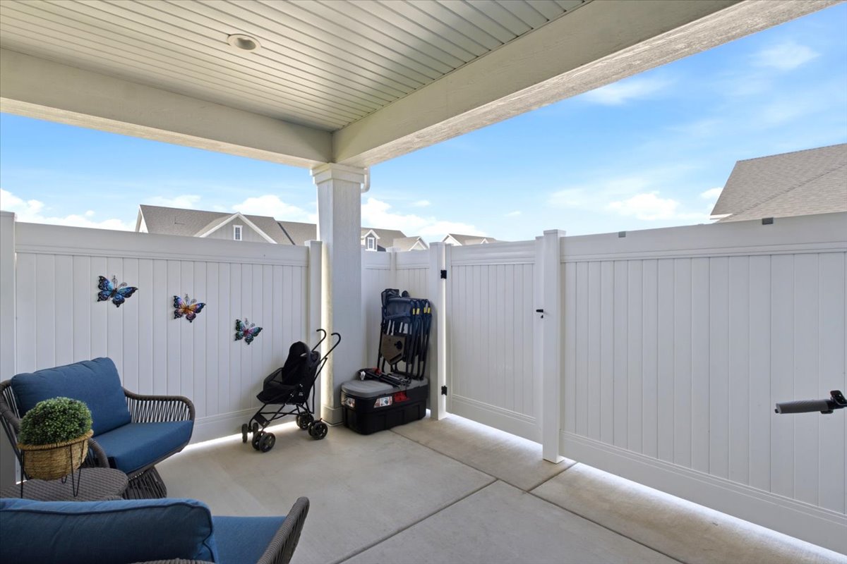 Covered patio featuring concrete flooring and a white privacy fence