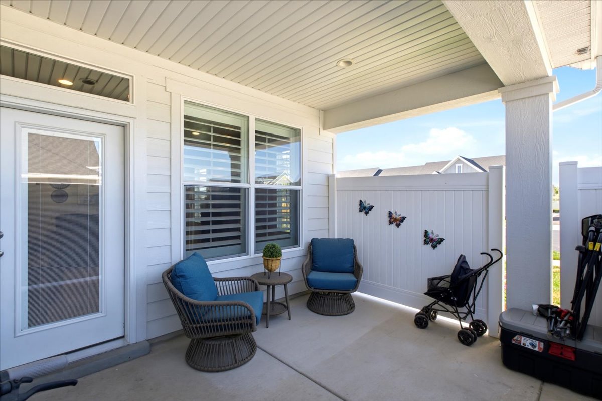 Covered patio with a concrete slab, white privacy fence, and white siding