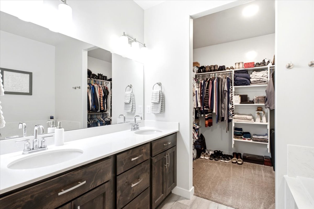 Double vanity featuring wood-finish cabinetry, white countertops, and chrome fixtures