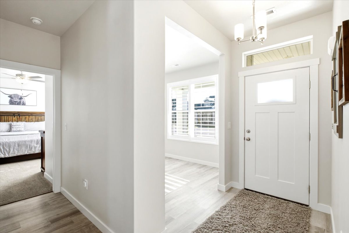 Entryway featuring a white paneled door with glass insert, a transom window, and a three-light chandelier