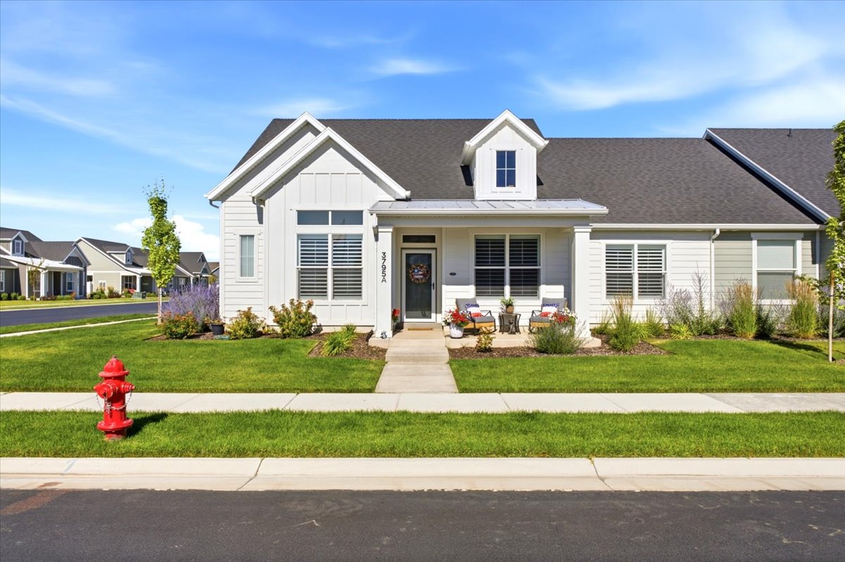 Modern farmhouse exterior featuring white board-and-batten siding, a dark shingle roof, and a prominent front dormer