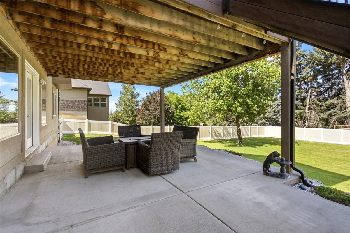 Covered concrete patio with exposed wood joist ceiling, providing an outdoor living area