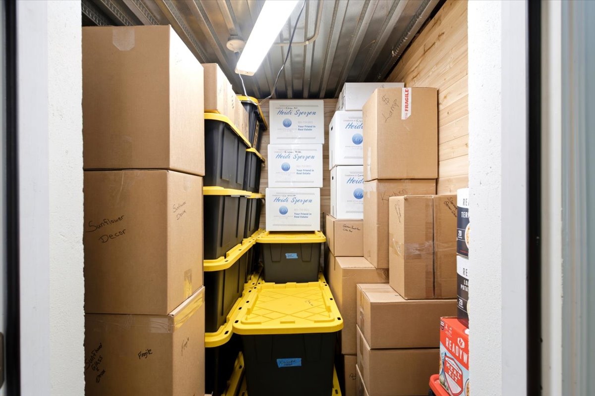 Interior storage space featuring wood-paneled walls, a corrugated metal ceiling, and fluorescent overhead lighting