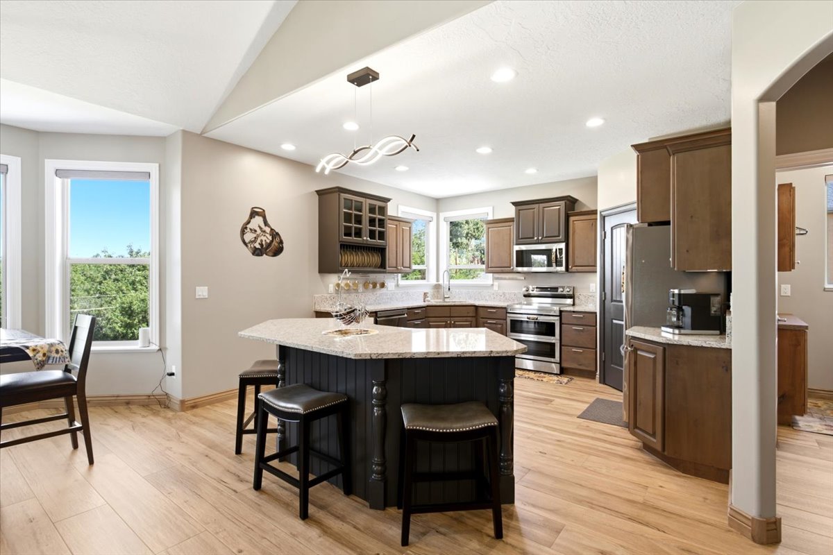 Kitchen with wood-finish flooring, recessed lighting, and a multi-level island with seating