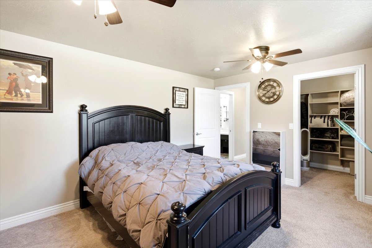 Bedroom featuring light beige walls, carpeted flooring, and a ceiling fan with integrated lighting