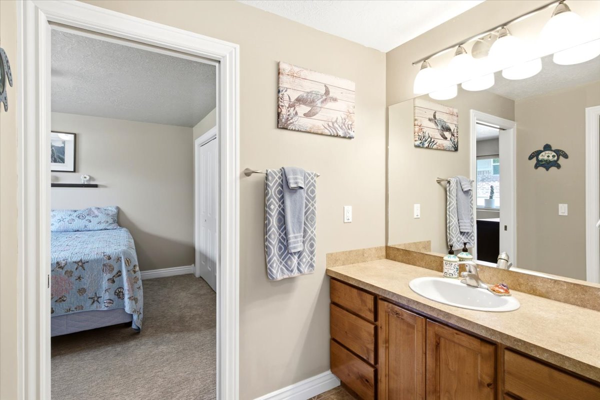 Bathroom vanity featuring a single basin sink, laminate countertop, and wood-finish cabinetry