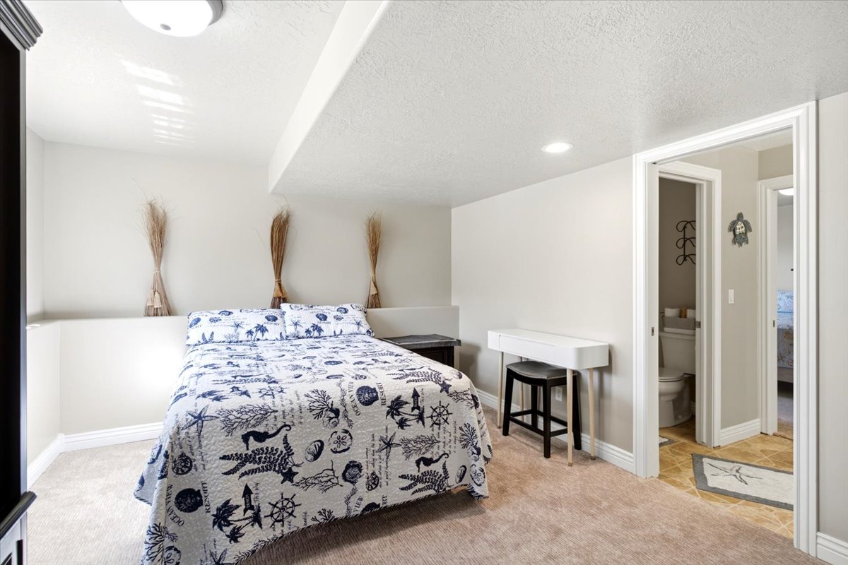 Carpeted sleeping area with recessed lighting and a built-in half-wall feature