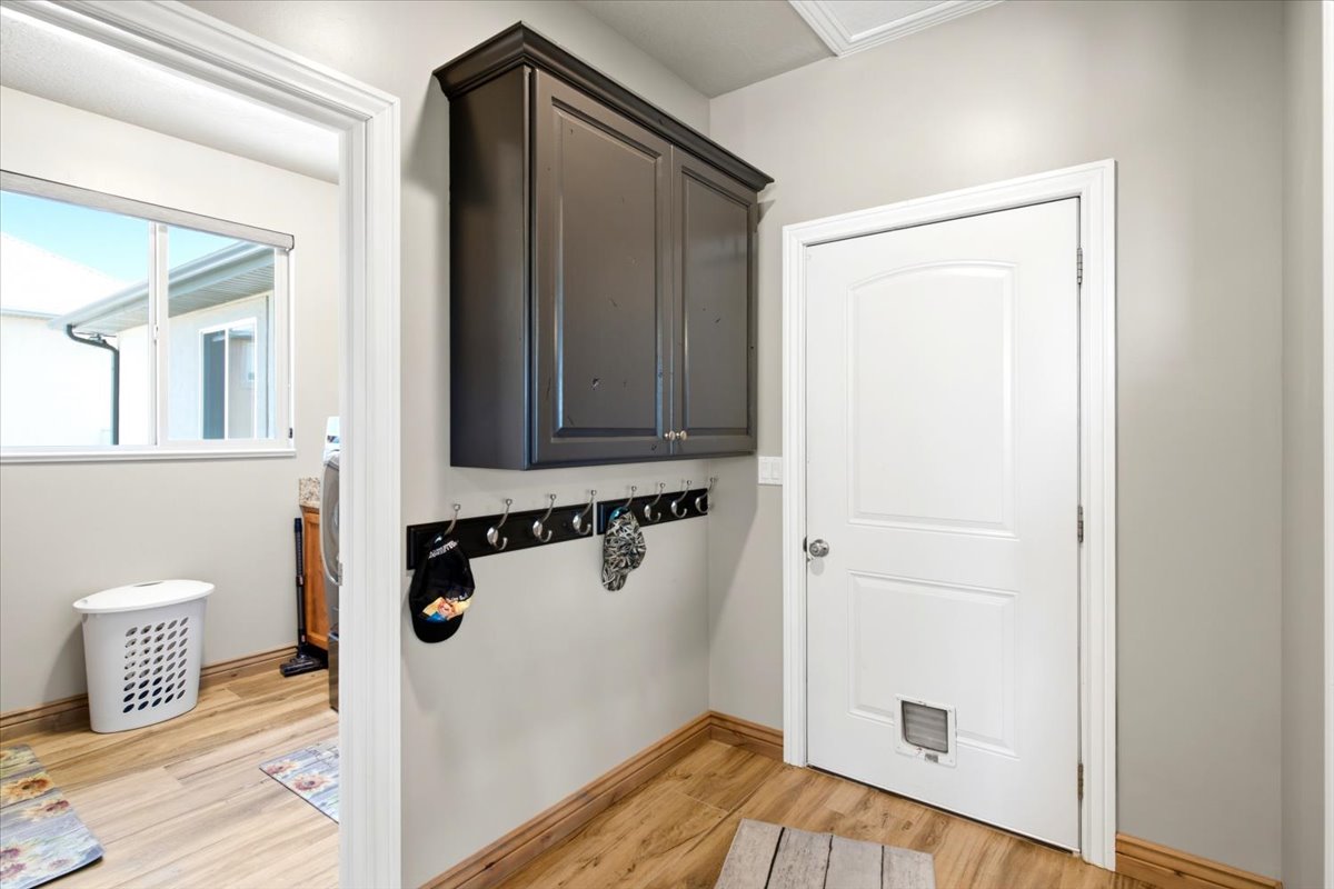 Entryway featuring wood-finish flooring, a wall-mounted coat rack, and built-in upper cabinetry