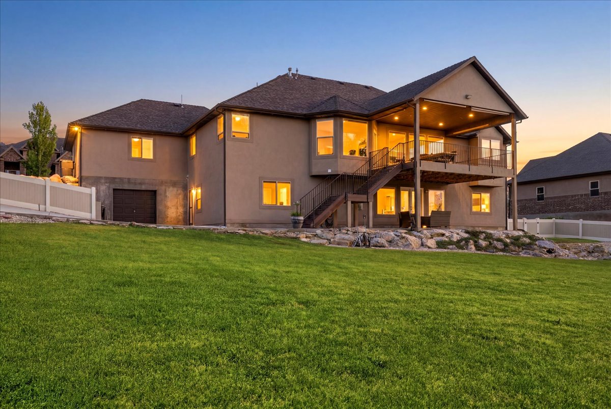 Stucco exterior residence with a multi-level deck, lower-level patio, and an integrated garage