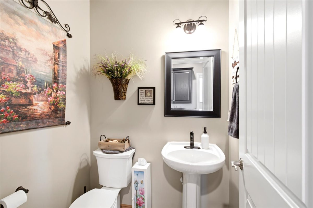 Pedestal sink with a black-framed mirror and wall-mounted light fixture