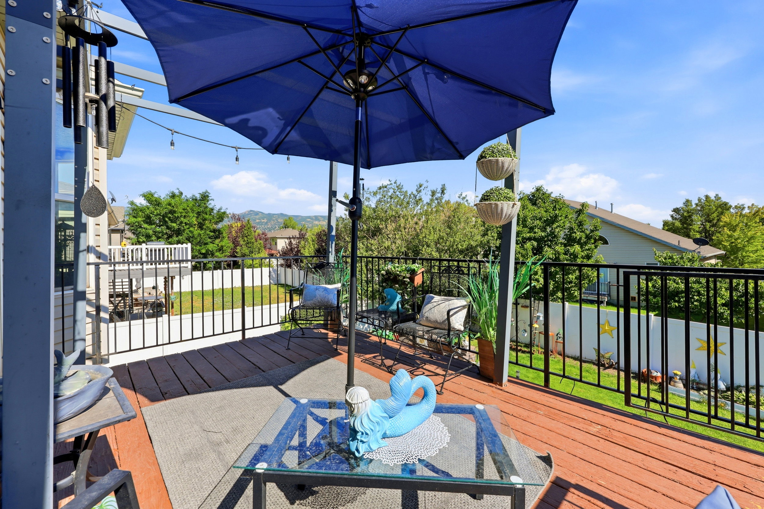 Expansive wooden deck featuring black metal railings and overhead string lighting