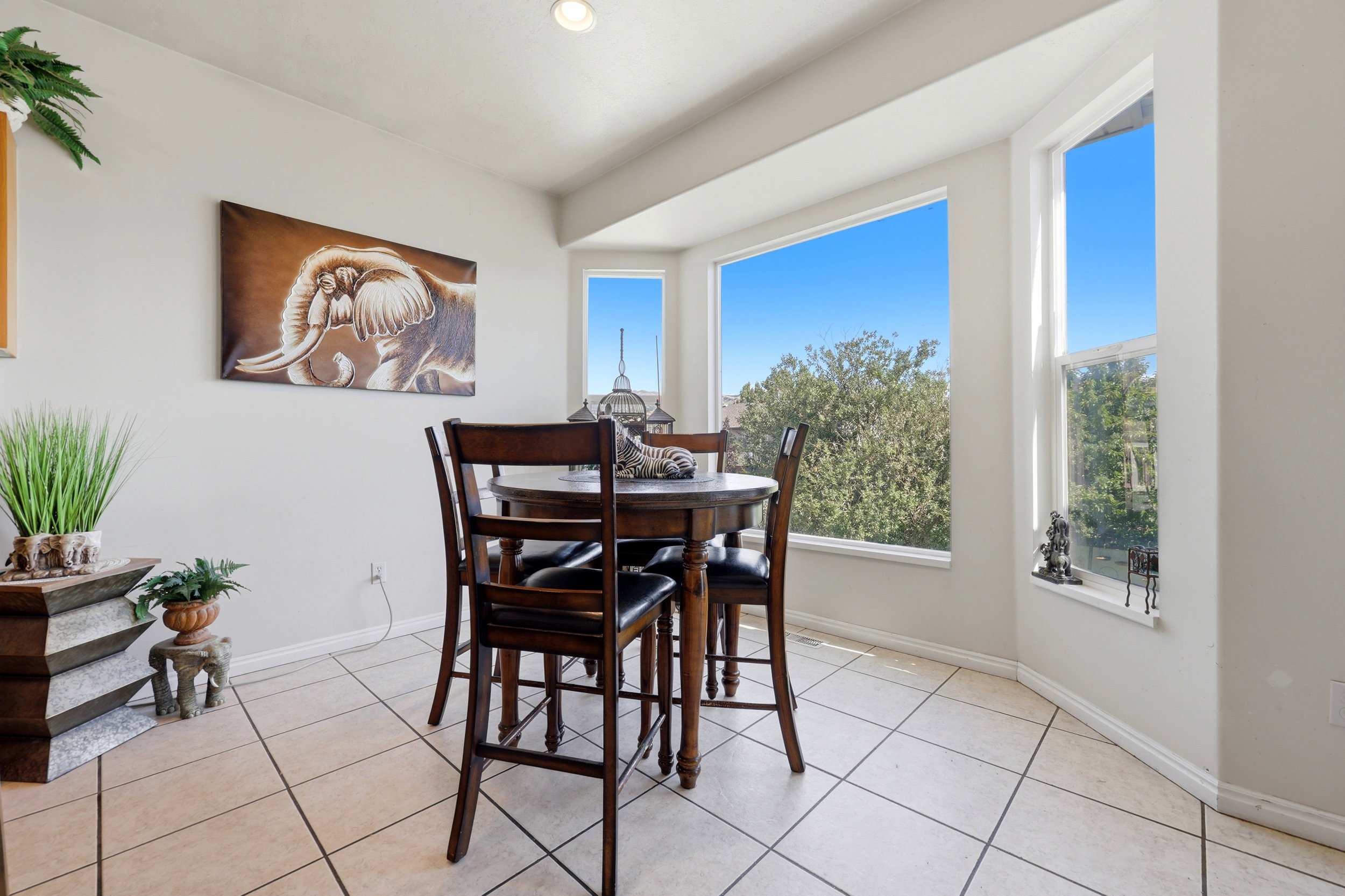 Bright eating area featuring a bay window with multiple panes, tiled flooring, and recessed ceiling lighting
