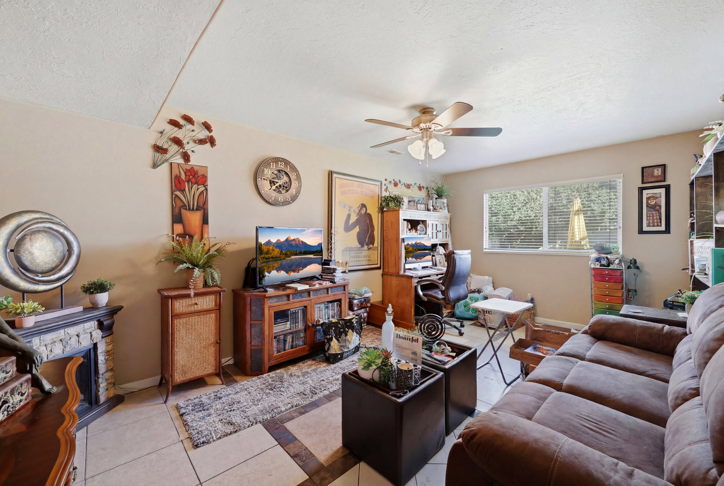 Living area featuring a light-toned tile floor with contrasting dark tile accents, a window with blinds, and a ceiling fan