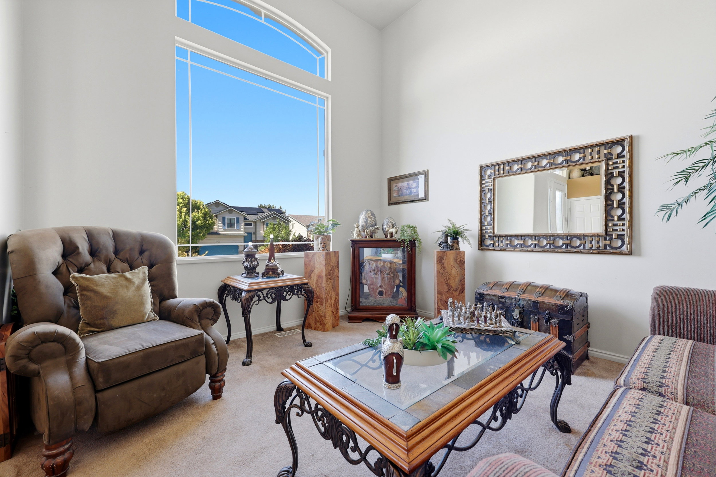 Vaulted ceiling living space featuring a large arched window, neutral wall paint, and carpet flooring