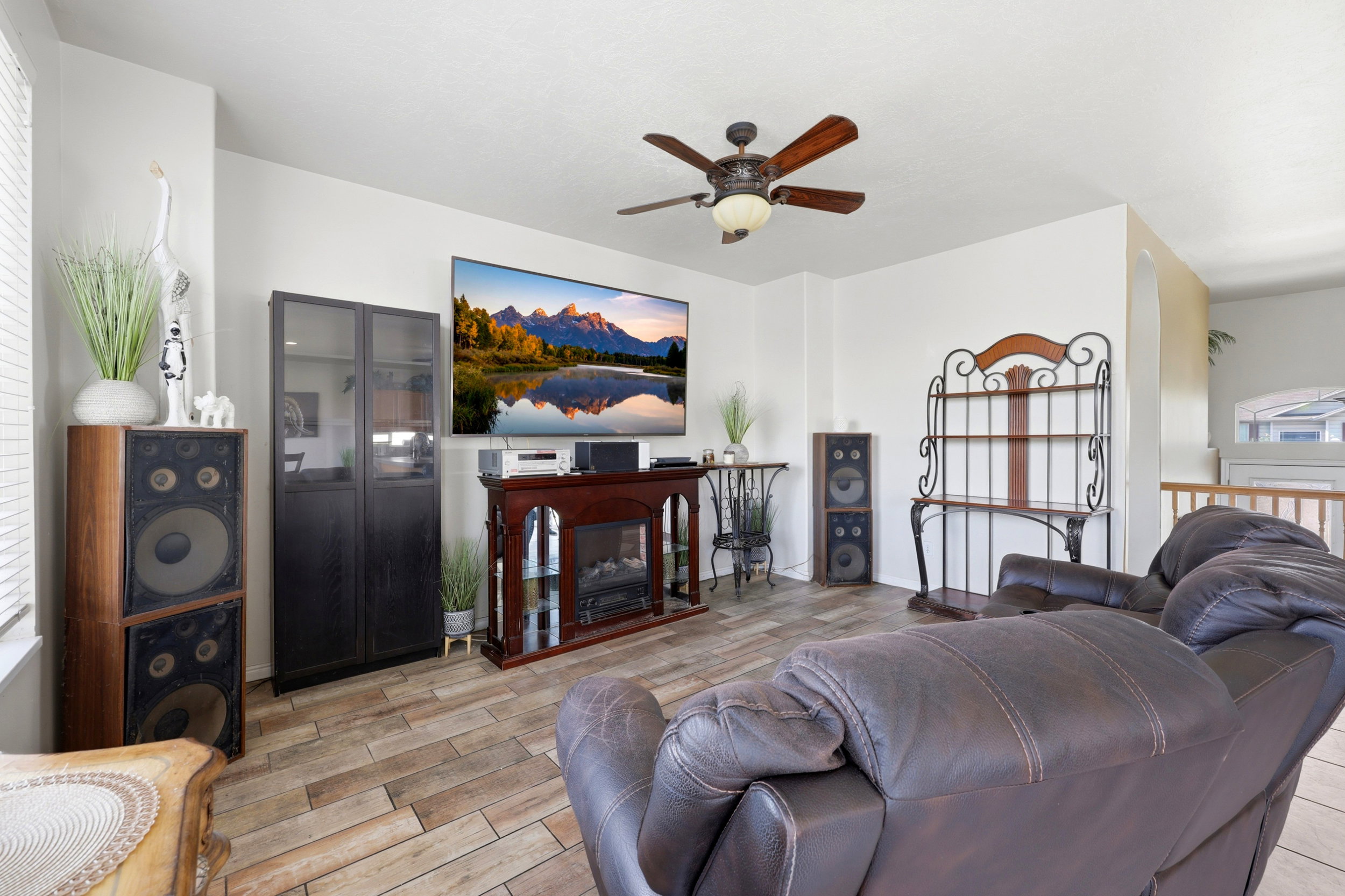 Living area featuring wood-finish tile flooring, a ceiling fan with integrated lighting, and white wall finishes