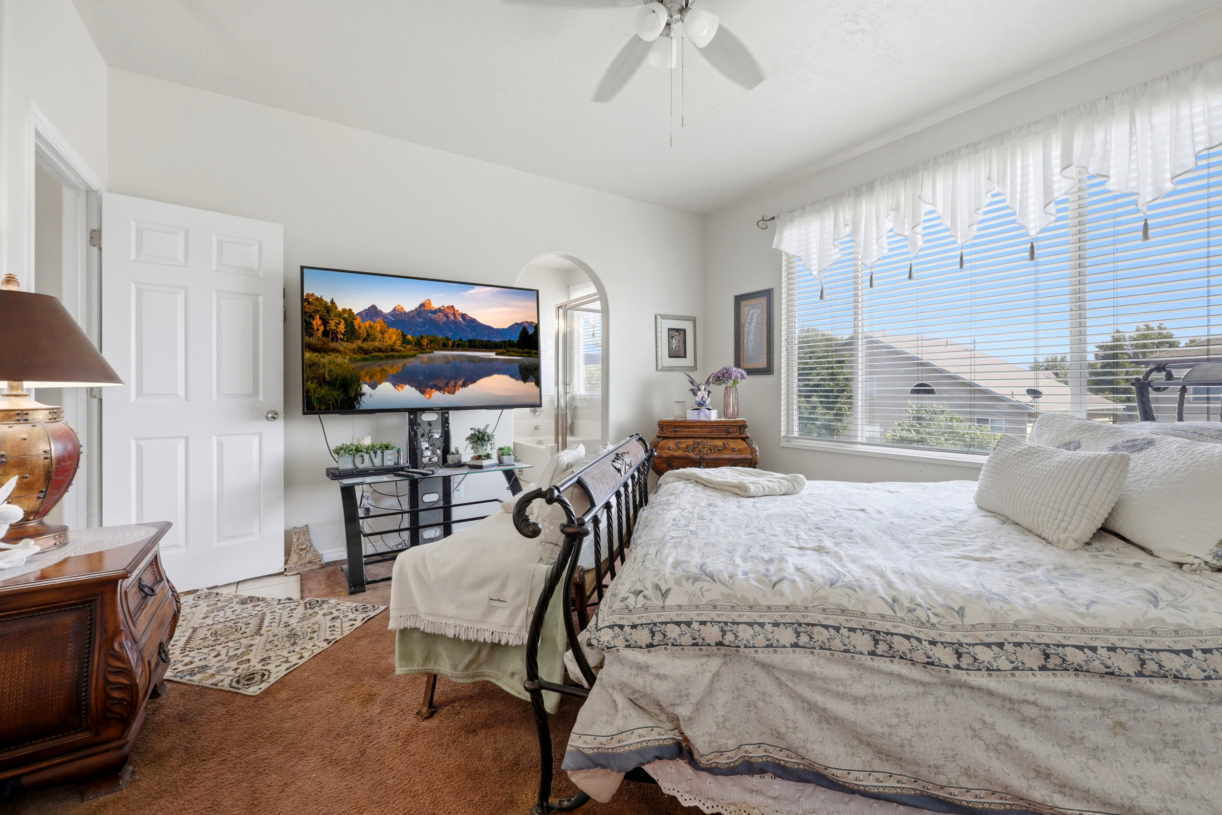 Carpeted interior space featuring a ceiling fan, a window with horizontal blinds, and a white six-panel interior door