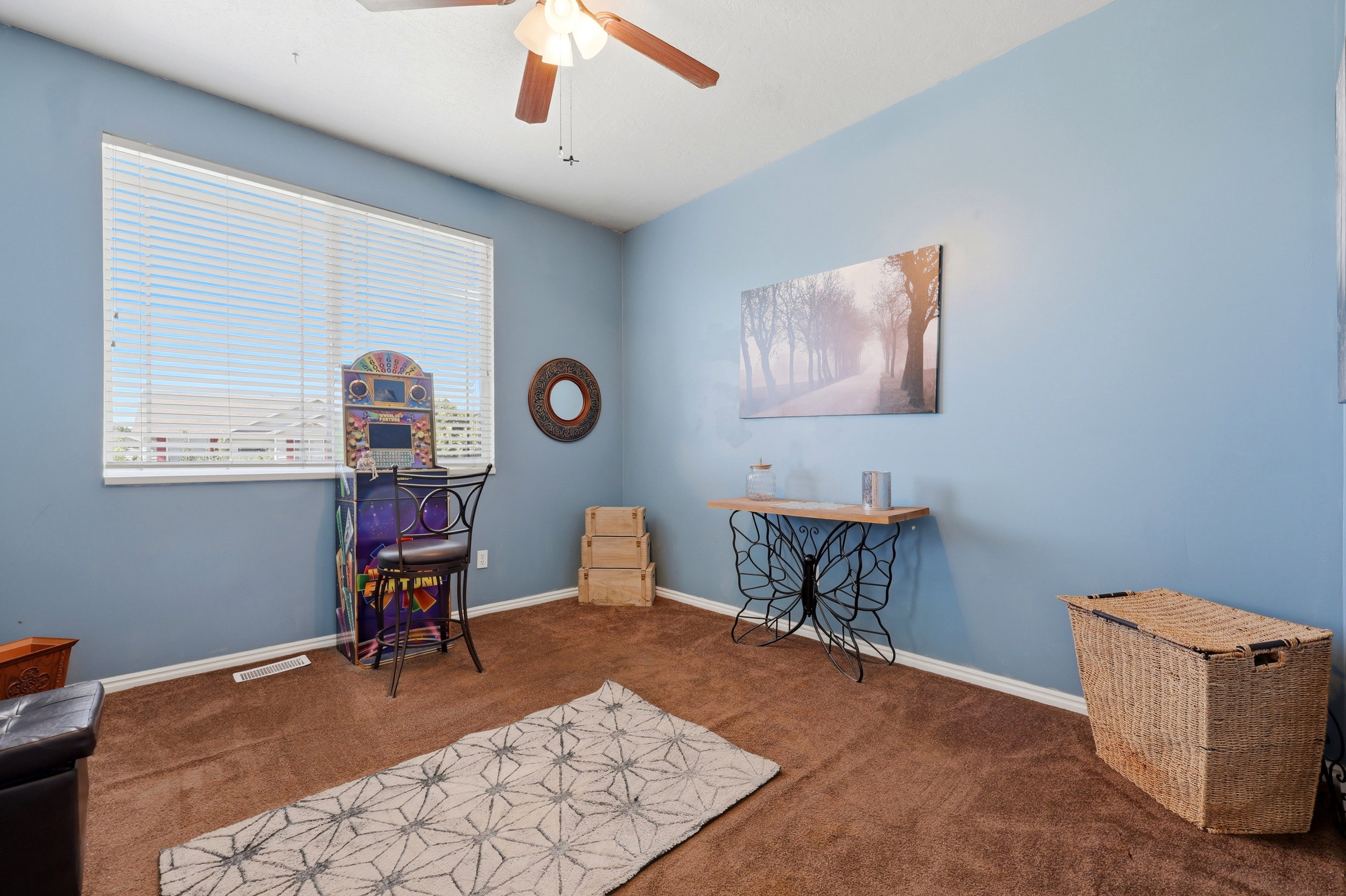 Room featuring a wide window with horizontal blinds, a ceiling fan, light blue walls, and brown carpeting