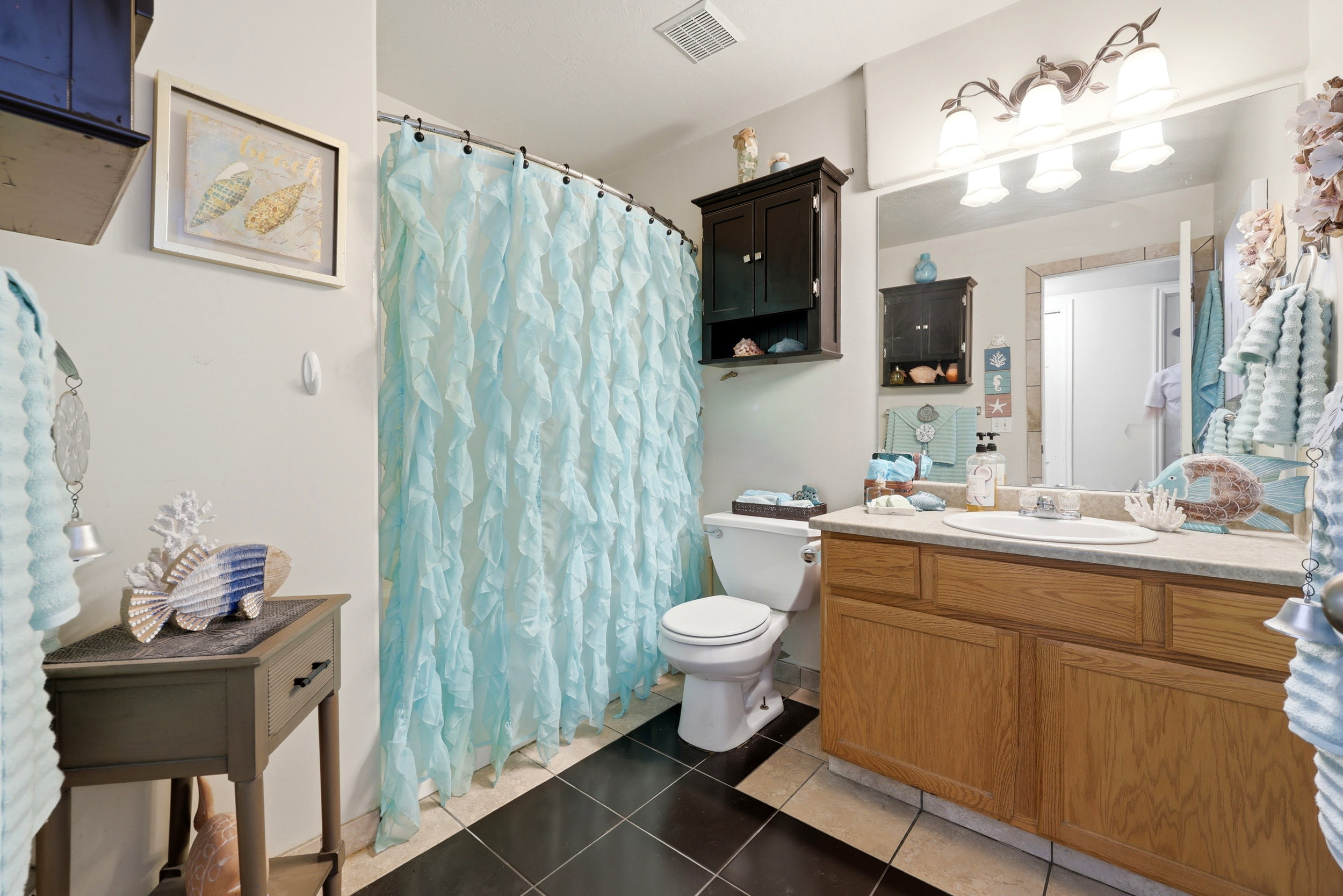 Bathroom featuring a vanity with wood-finish cabinetry and a single basin sink