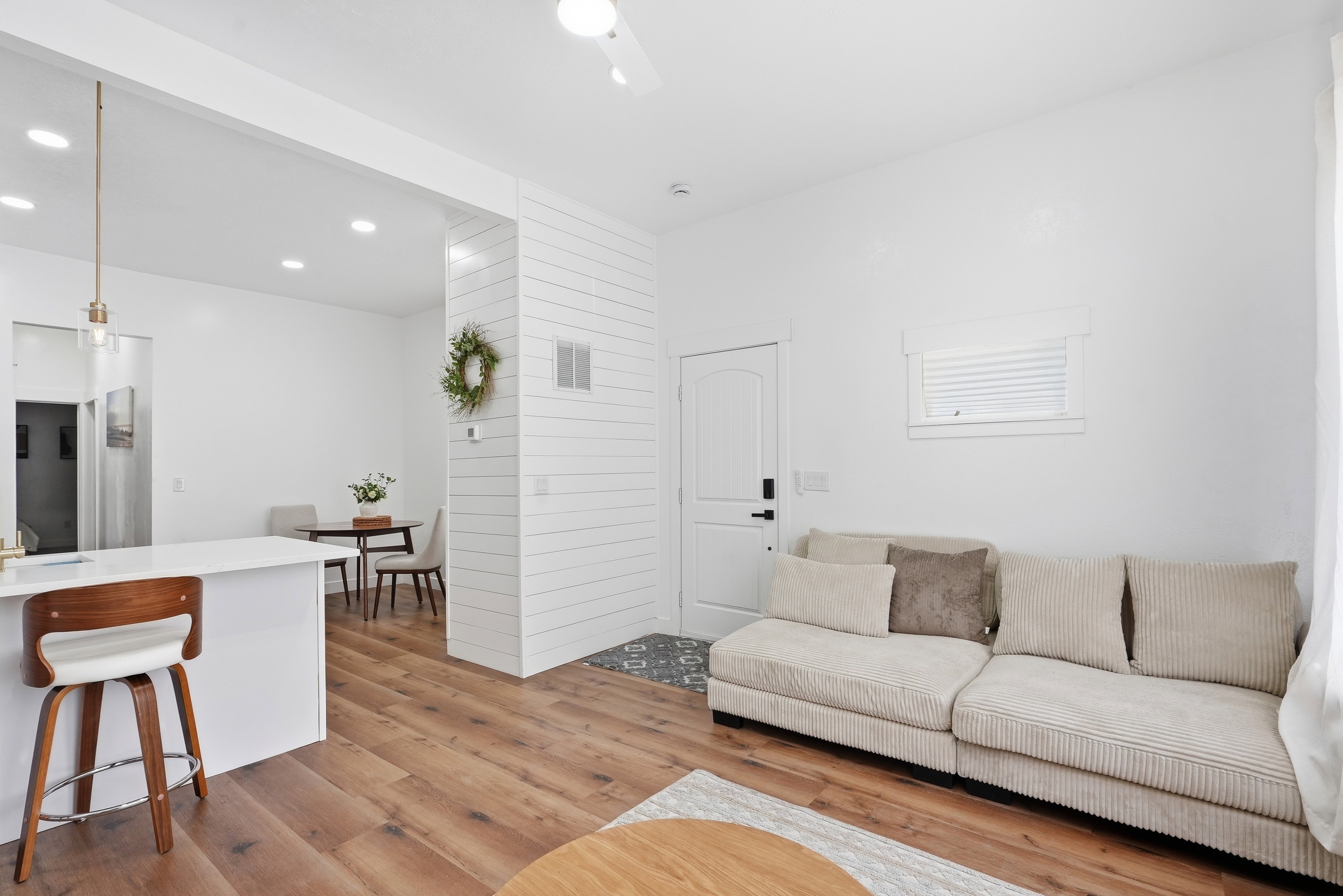 Open-concept living space featuring wood-finish flooring, recessed lighting, and a white shiplap accent wall