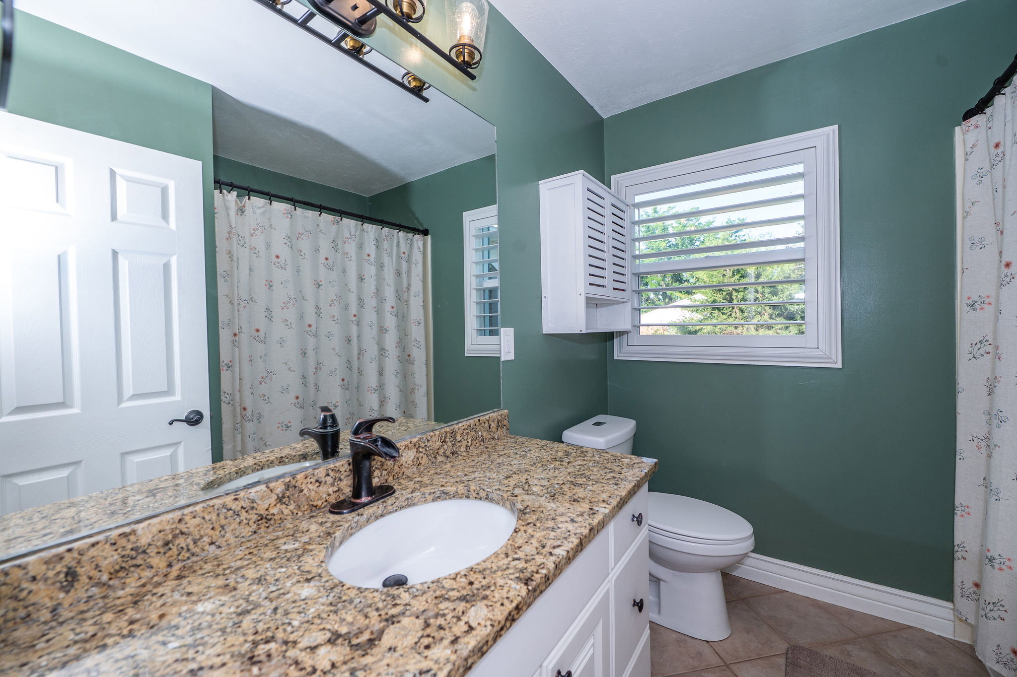 Bathroom featuring a vanity with a granite countertop, undermount sink, and oil-rubbed bronze faucet