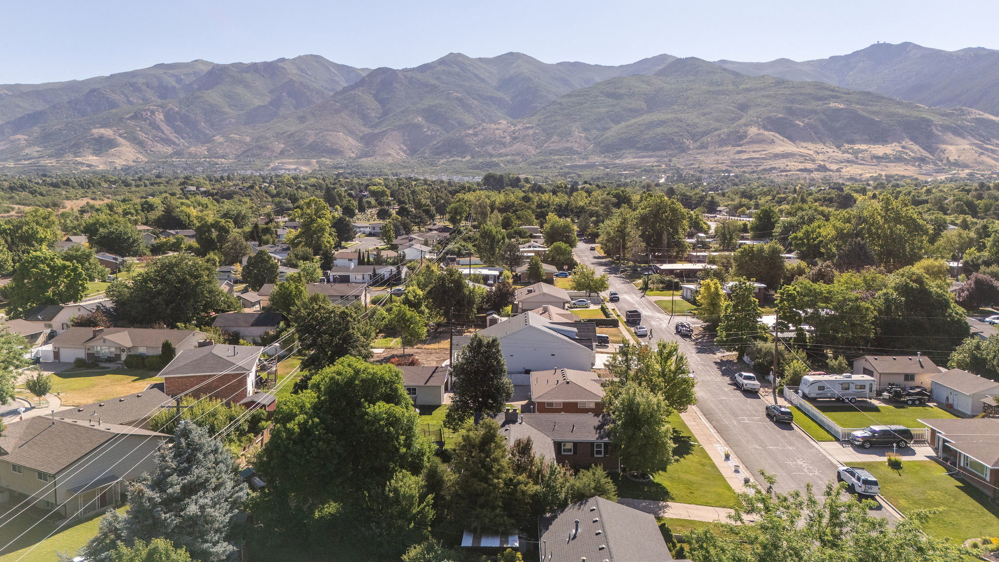 Expansive mountainous terrain with a residential neighborhood featuring established homes, mature trees, and paved streets