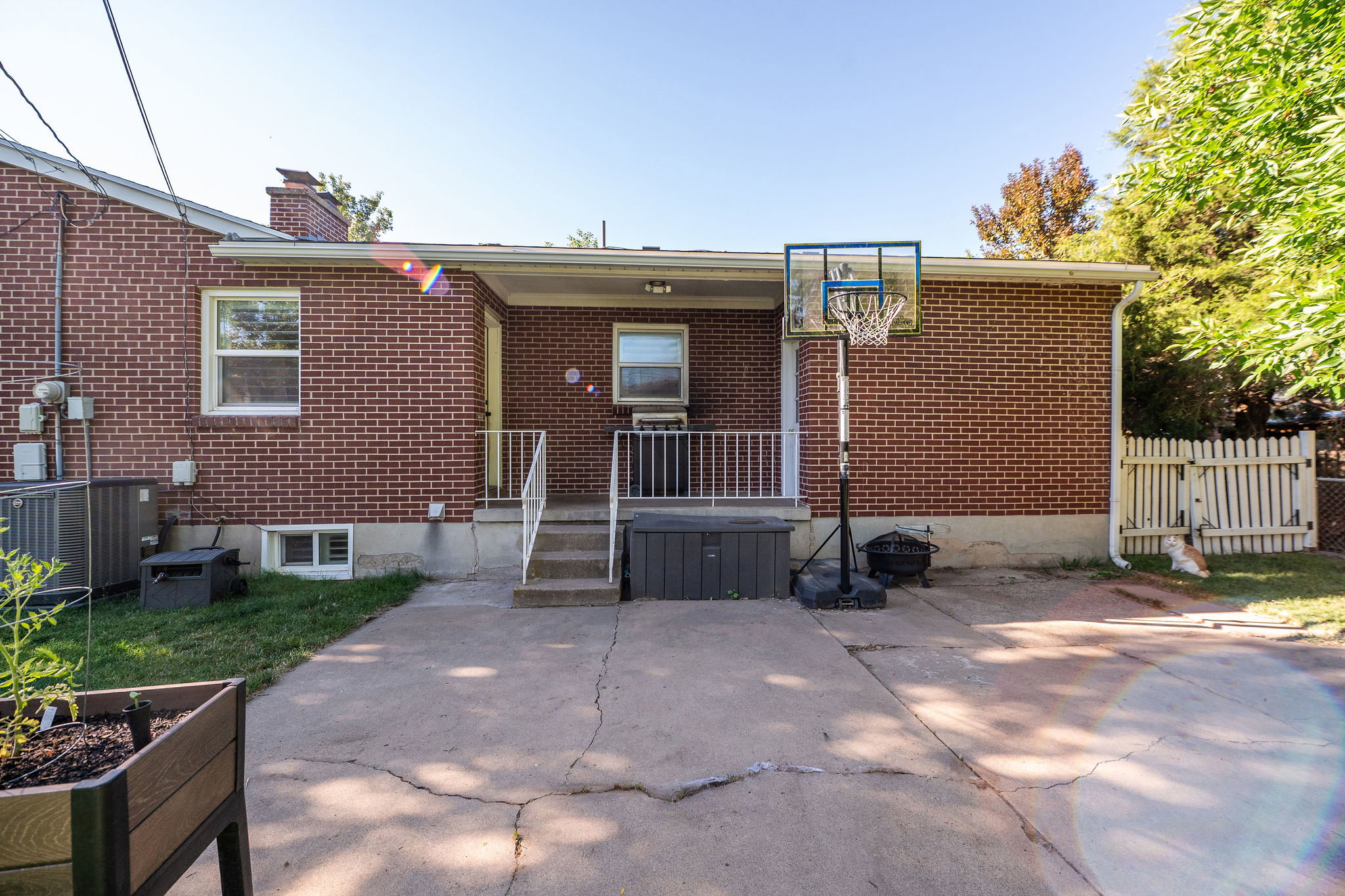 Brick exterior featuring multiple windows, a covered patio with white railings, and a concrete patio