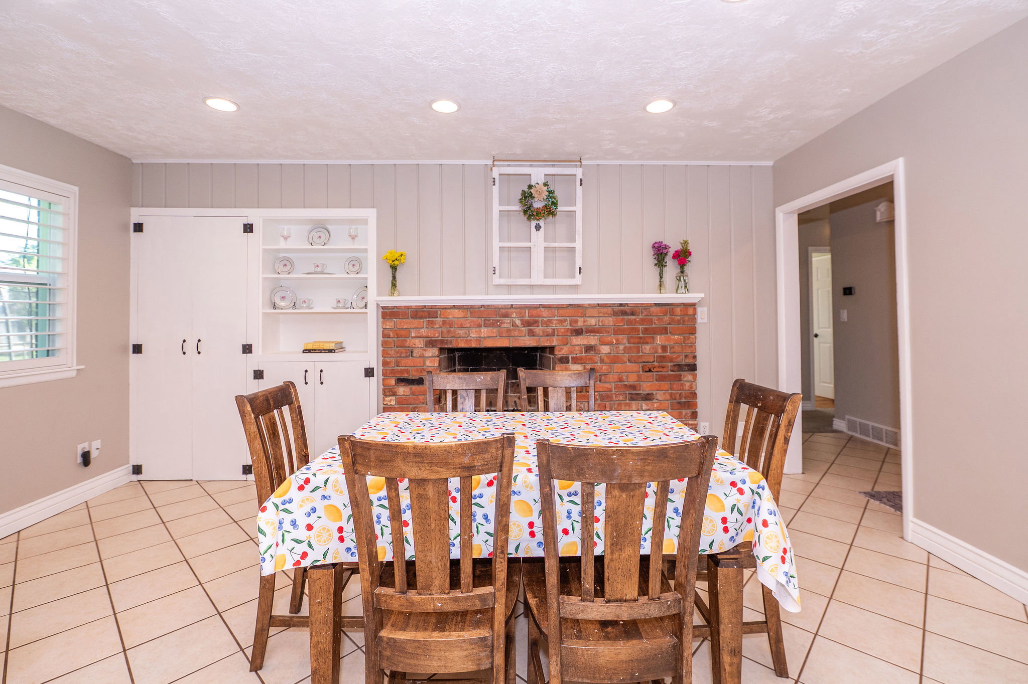 Recessed lighting illuminates a dining area featuring a brick fireplace