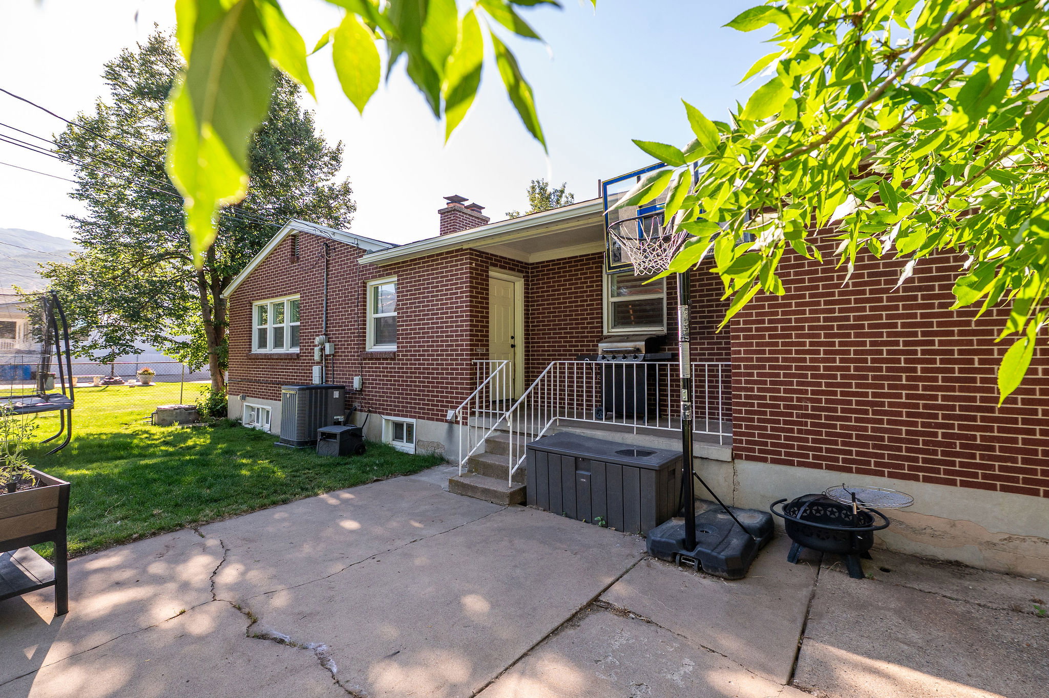 Brick exterior featuring a concrete patio, rear entry, and a grass lawn