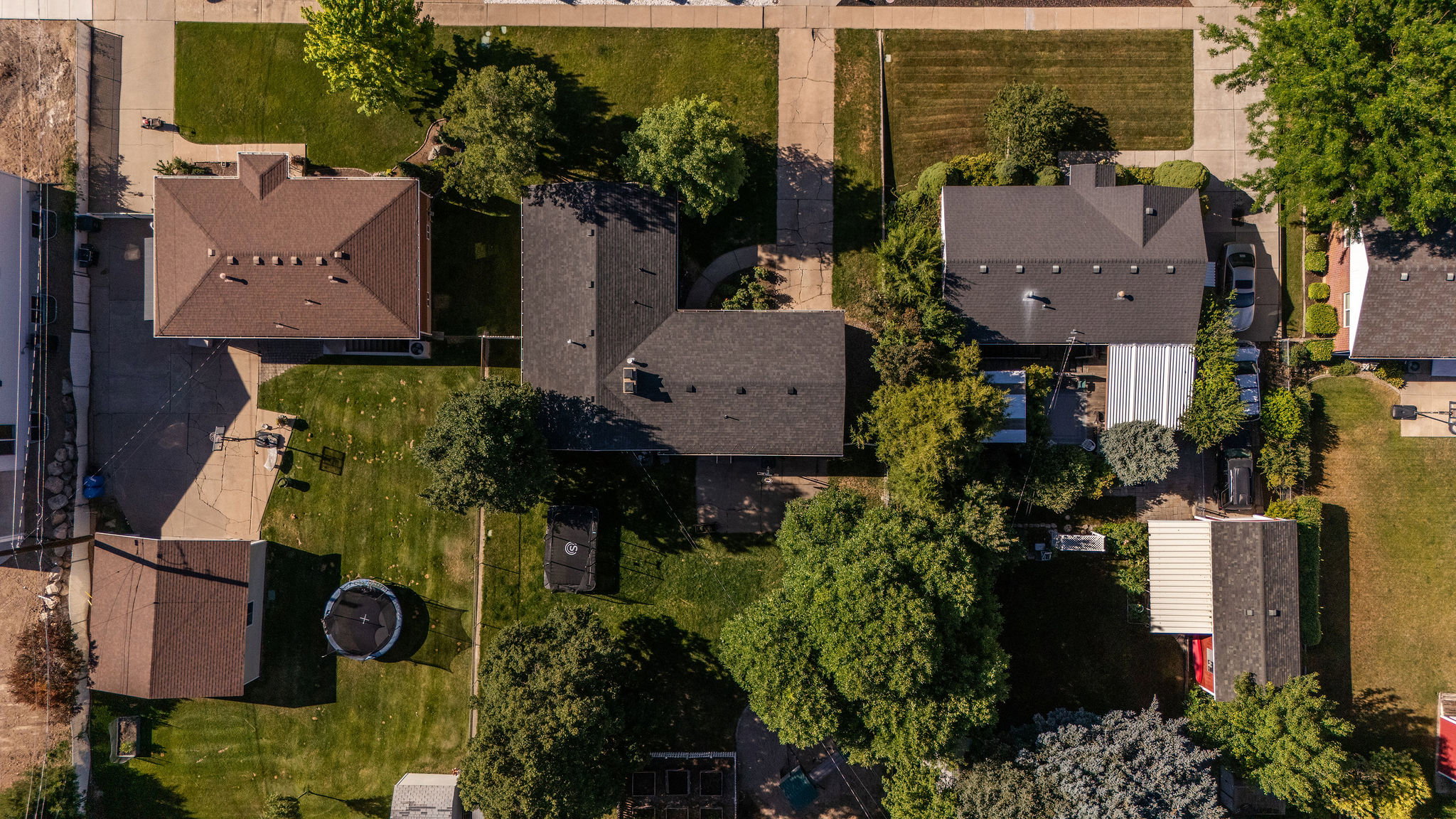 Expansive property featuring a large, manicured lawn with mature trees, a detached garage, and a paved driveway