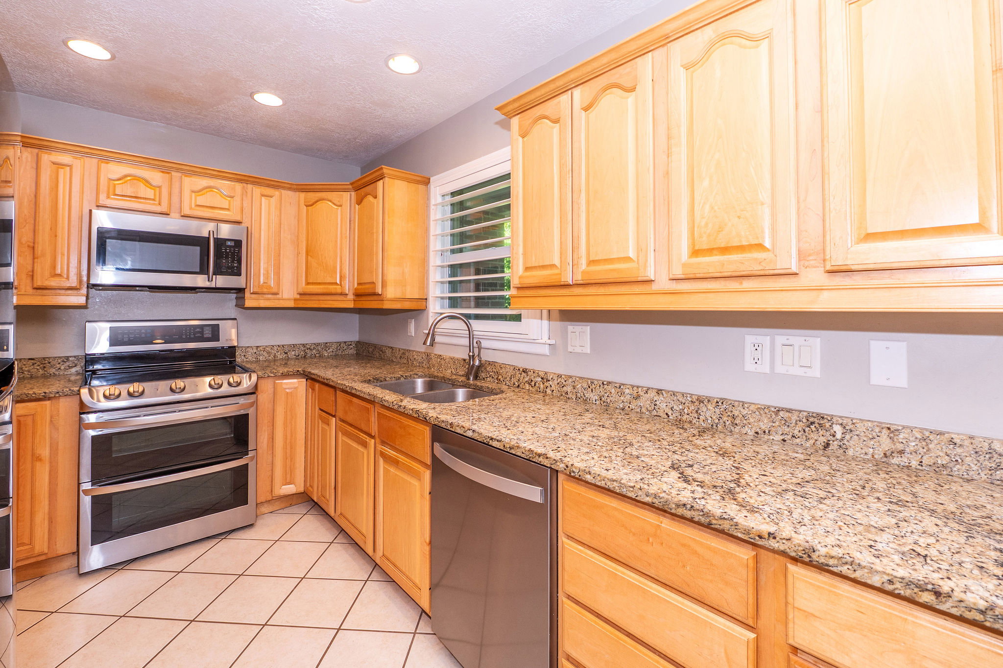Kitchen featuring light wood cabinetry, granite countertops, stainless steel appliances, and recessed lighting