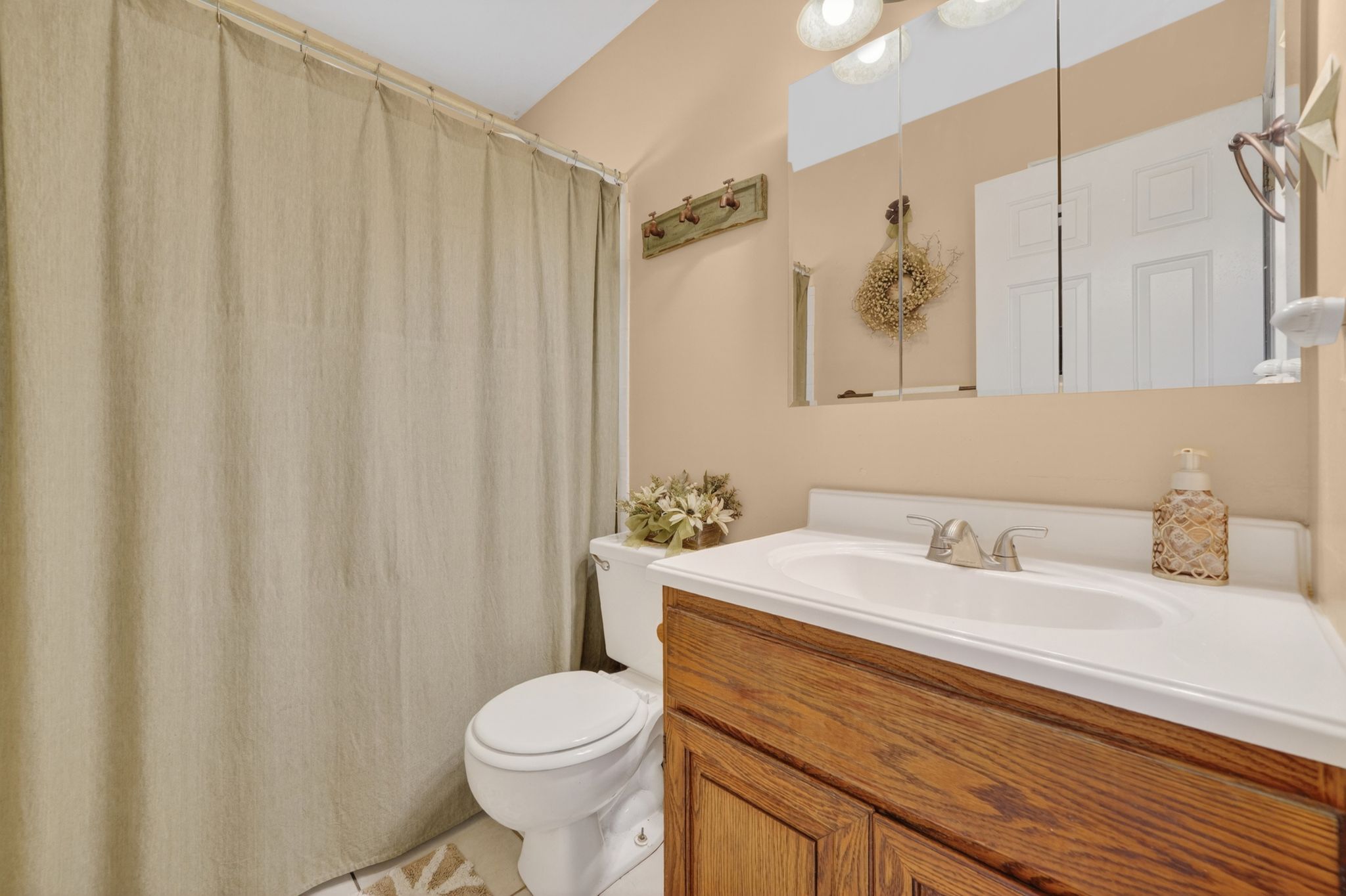 Bathroom featuring a wood-finish vanity with an integrated white sink and chrome faucet