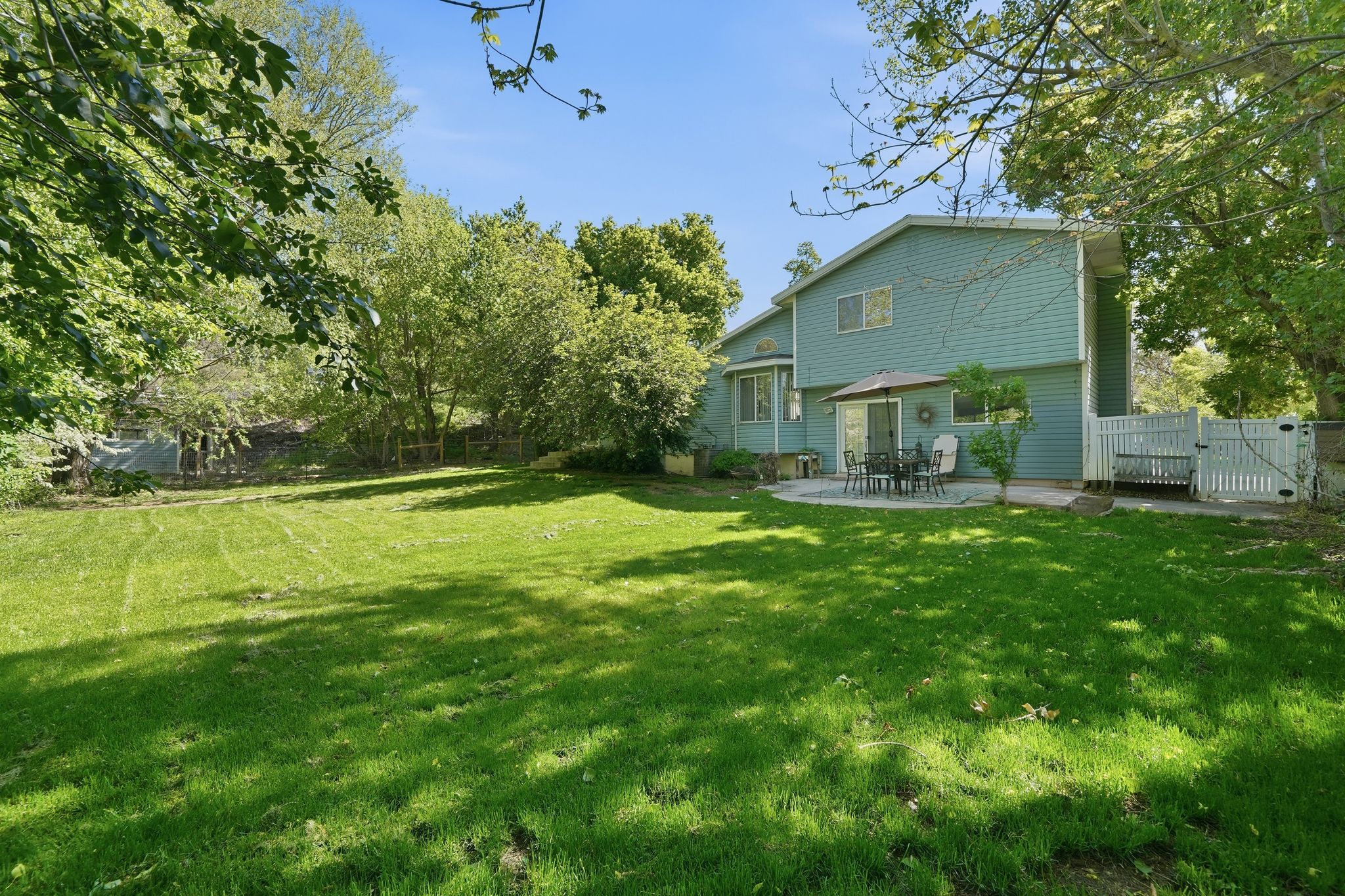 Spacious green lawn with mature trees bordering the property