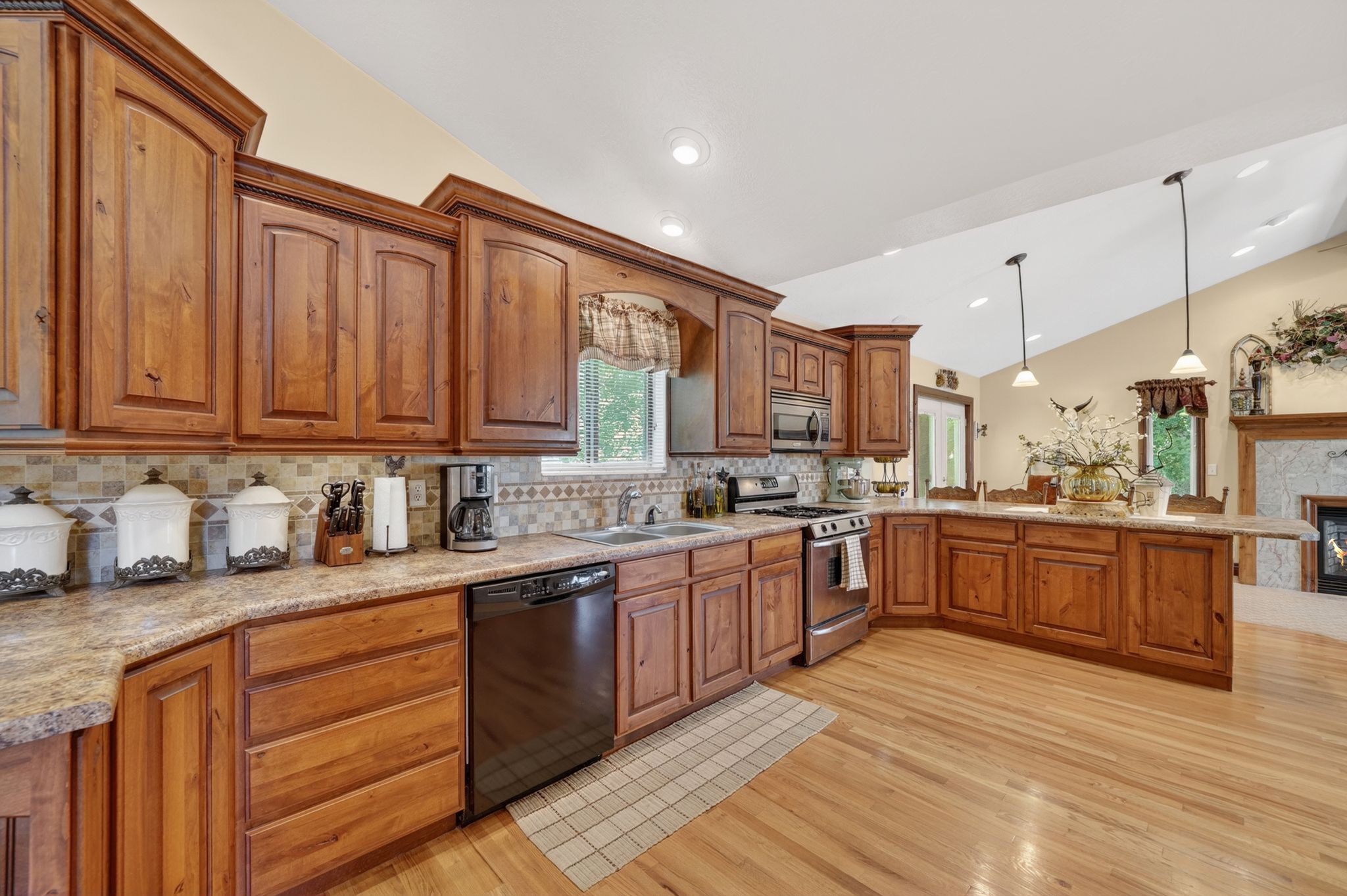 Kitchen featuring wood cabinetry, stainless steel appliances, a tile backsplash, and light-tone wood-finish flooring