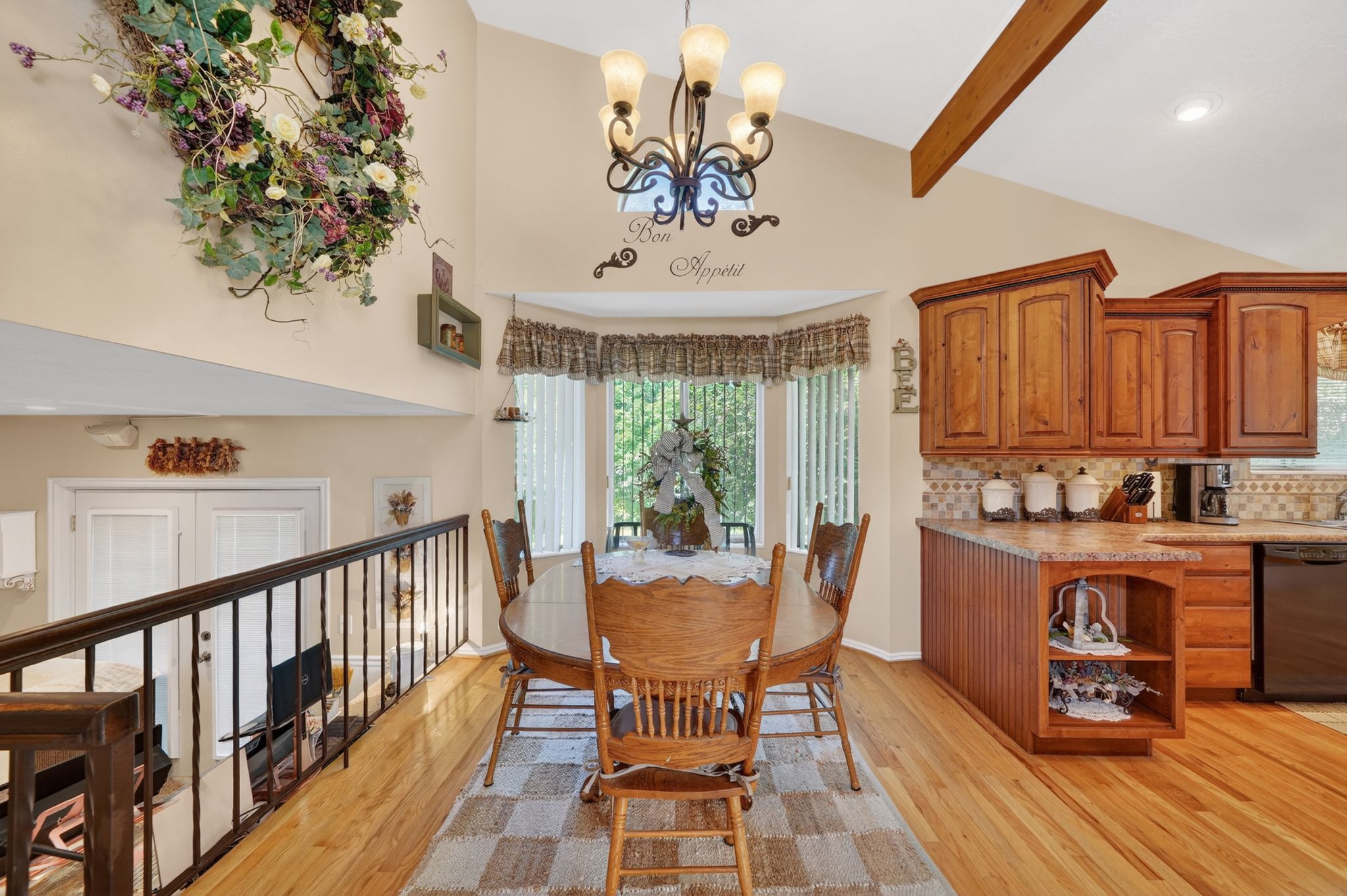 Dining area with vaulted ceilings, a bay window, and wood-finish flooring