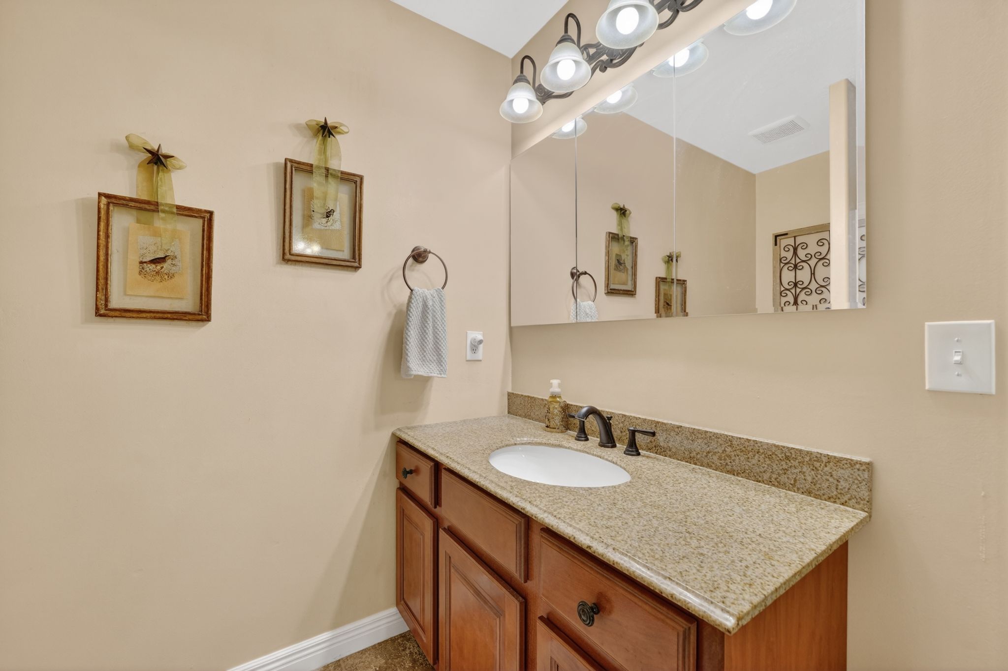 Bathroom vanity featuring a granite countertop, undermount sink, and dark bronze faucet