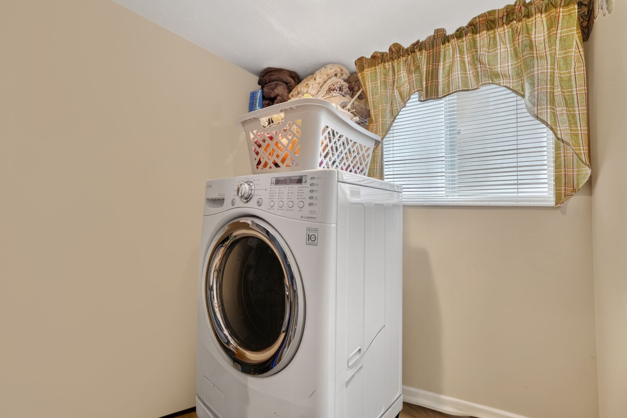 Dedicated laundry area featuring light-toned walls and a window with blinds