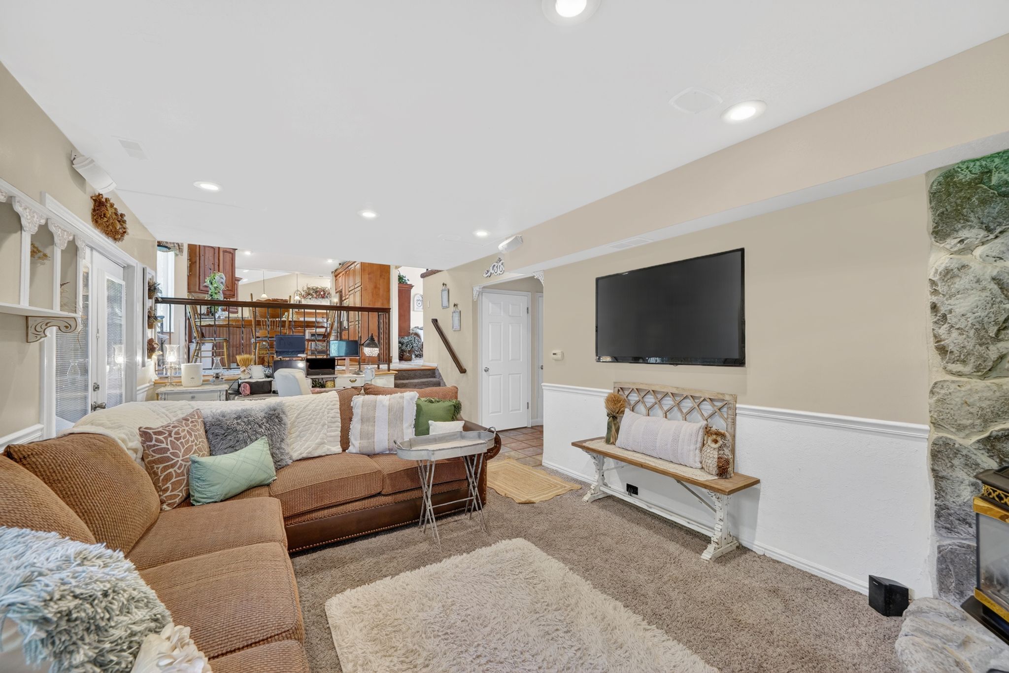 Spacious lower-level living area with recessed lighting, wainscoting, and a stone-clad fireplace