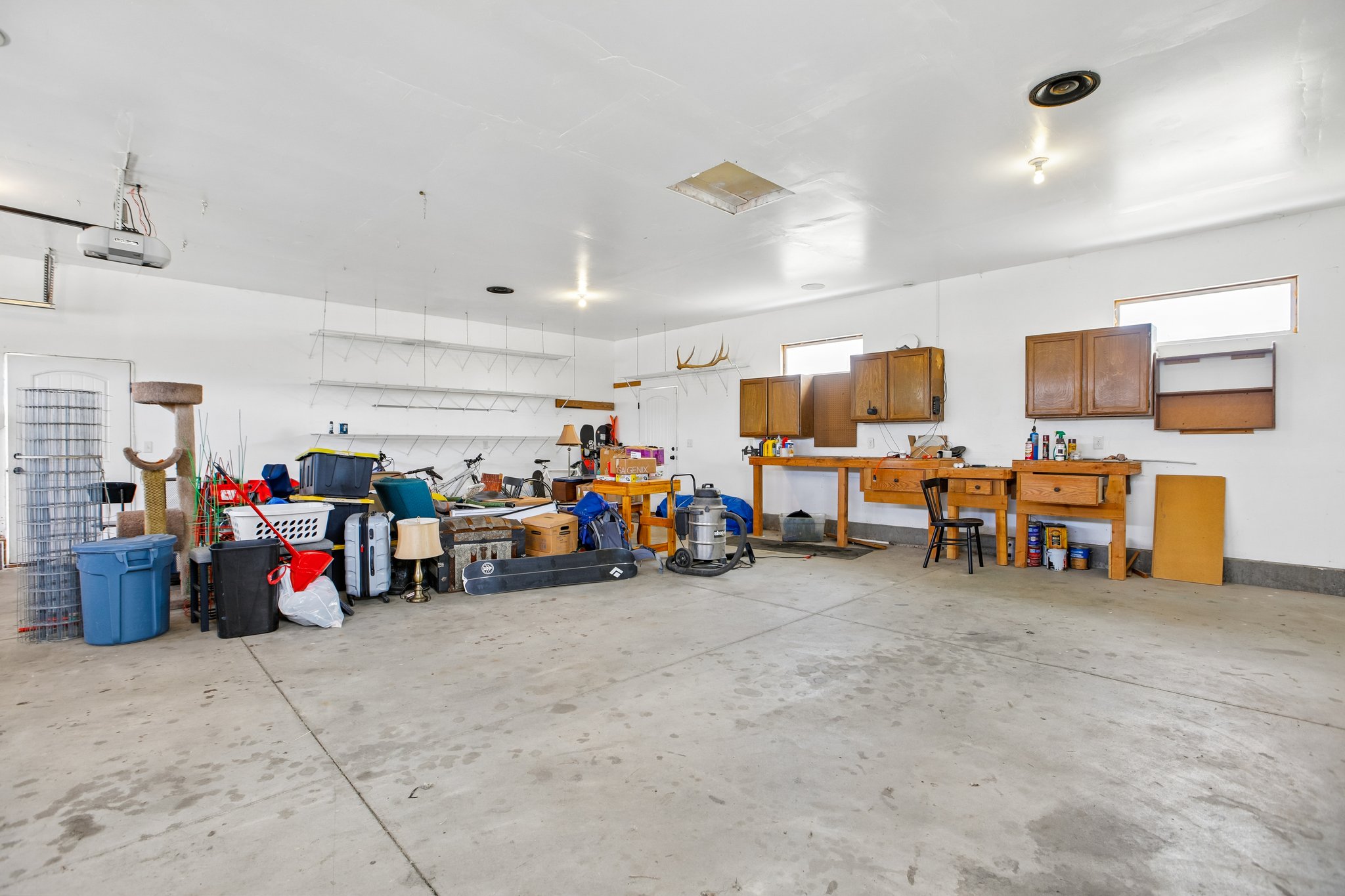 Spacious garage featuring a concrete floor, built-in shelving, white walls, and multiple windows