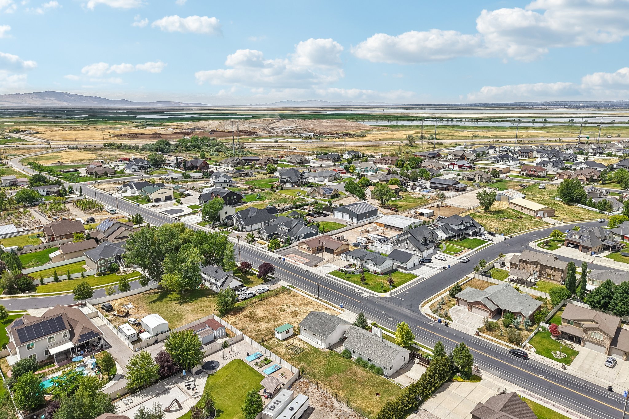 Expansive aerial perspective showcasing a residential development with mature trees, paved streets, and a mix of single-story and multi-story homes