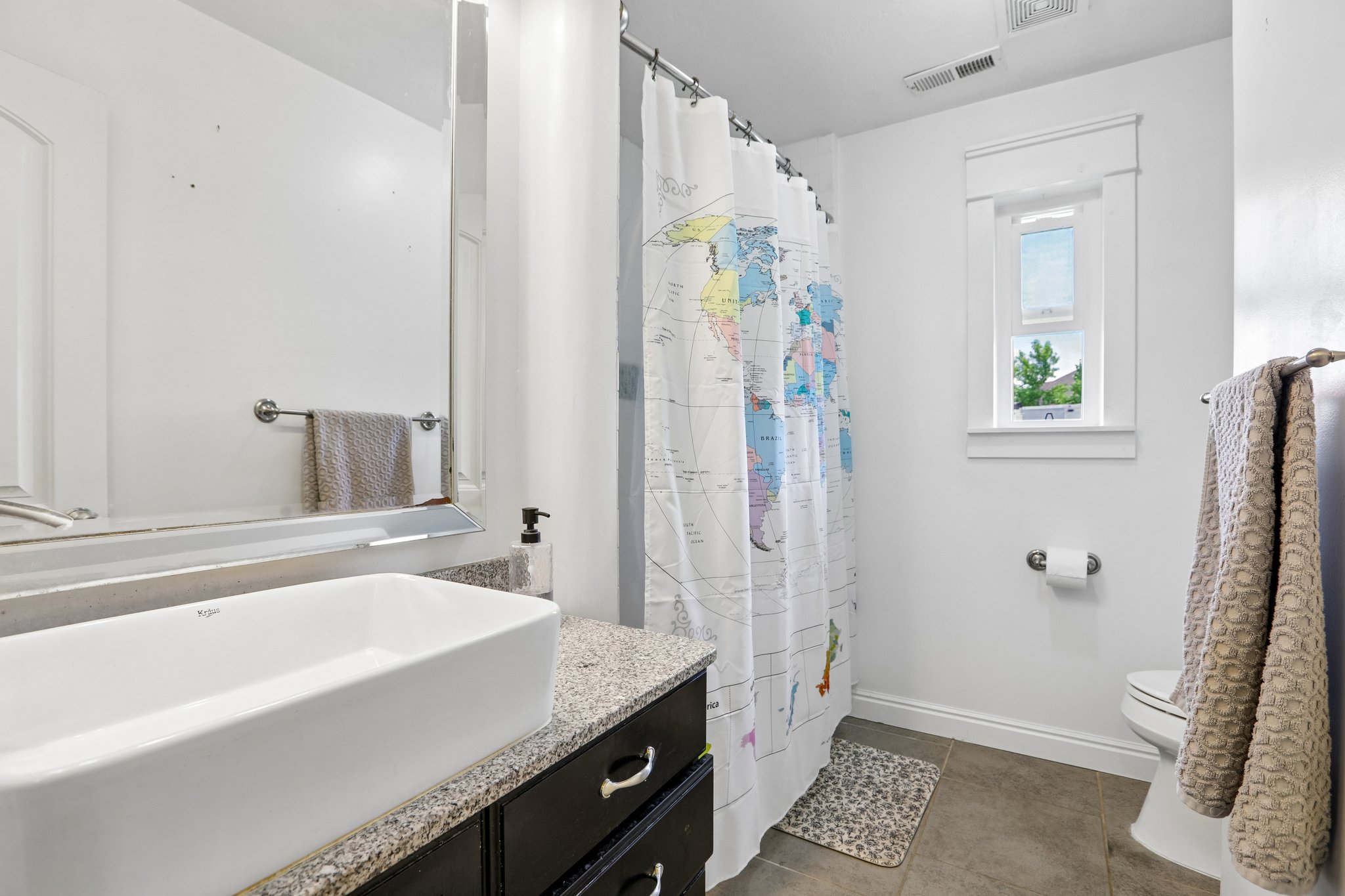 Bathroom featuring a rectangular vessel sink, granite-finish countertop, dark wood-finish vanity, and a framed window